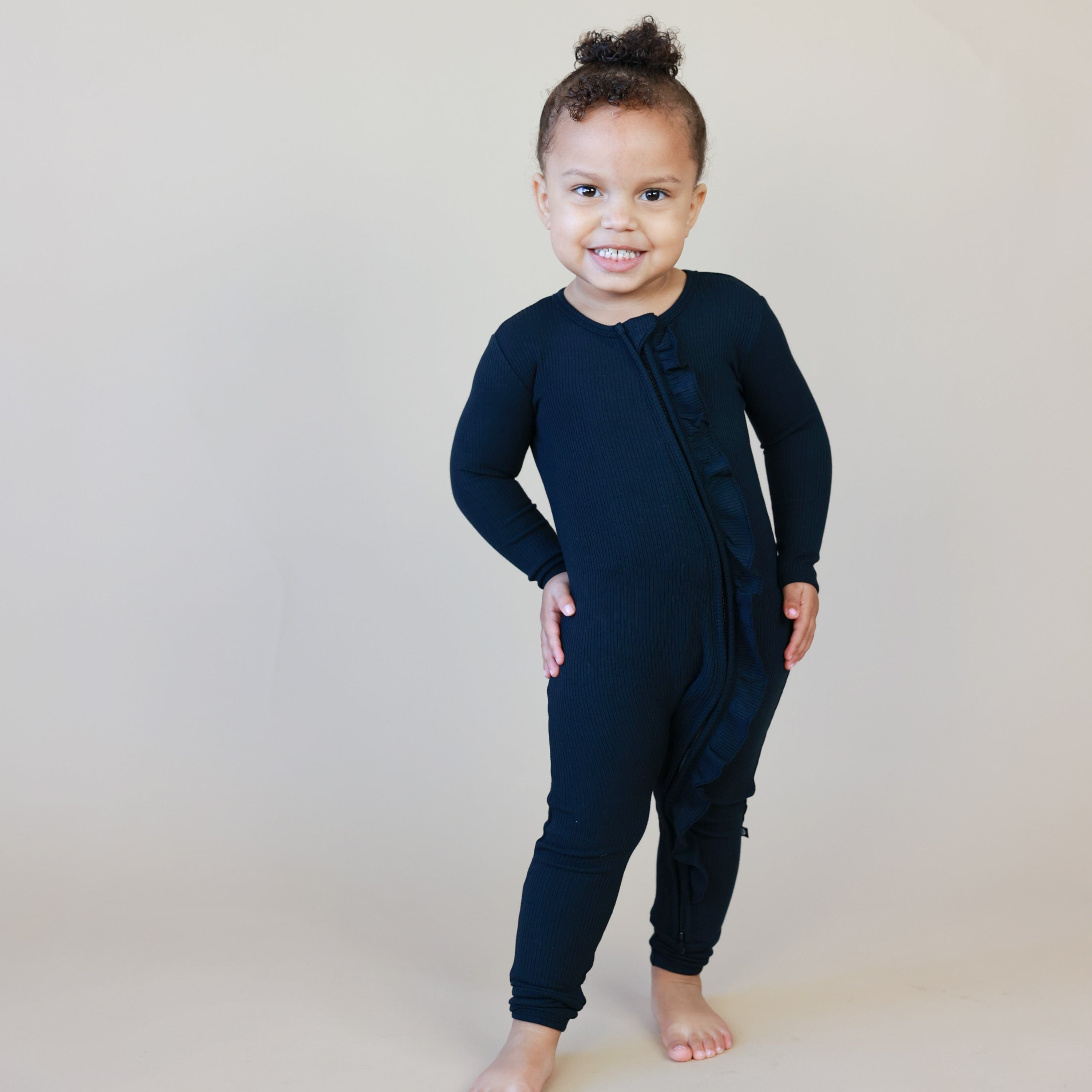 Toddler wearing Kyte Baby Ribbed Ruffle Zipper Romper in Midnight