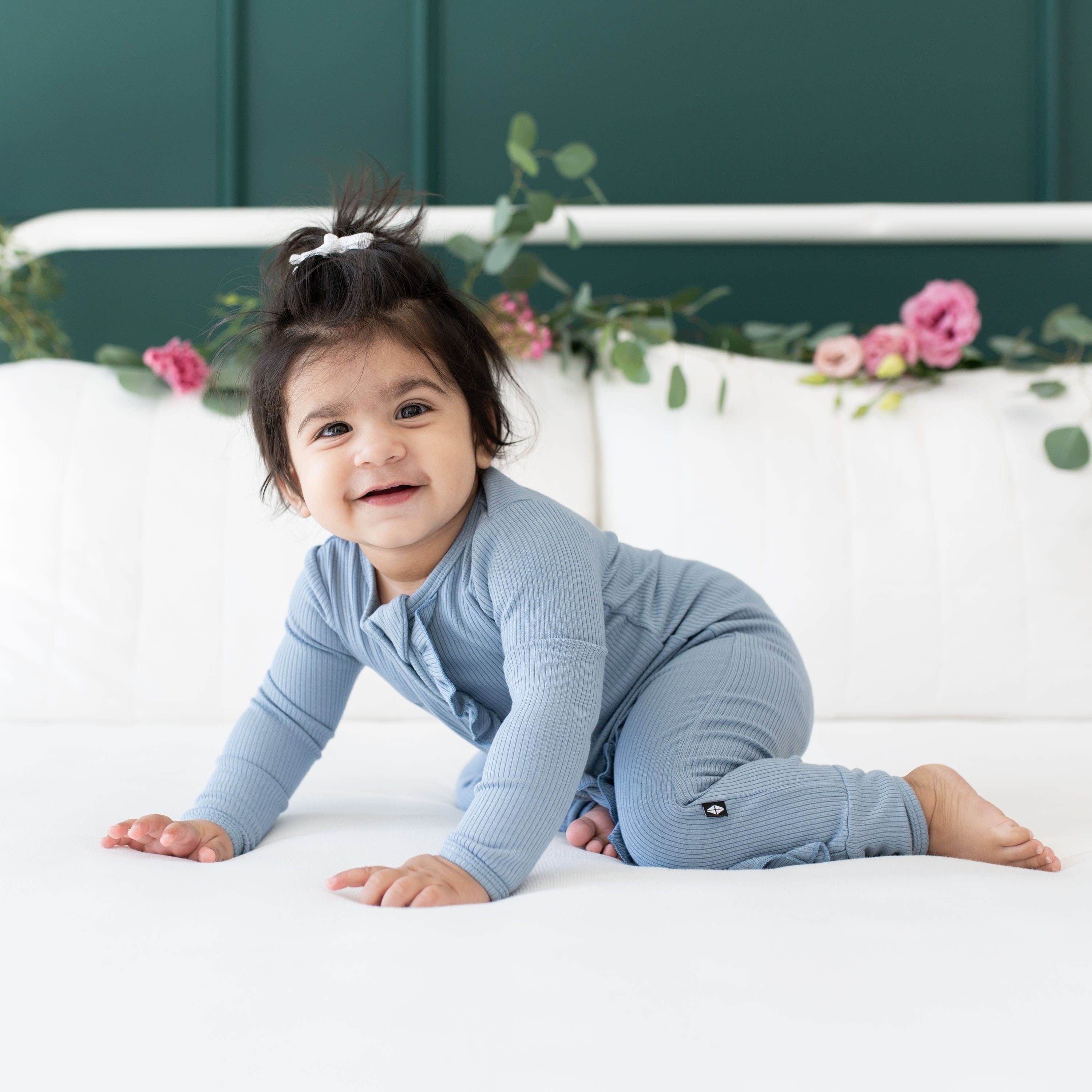 Girl wearing Kyte Baby bamboo Ribbed Ruffle Zipper Romper in Slate