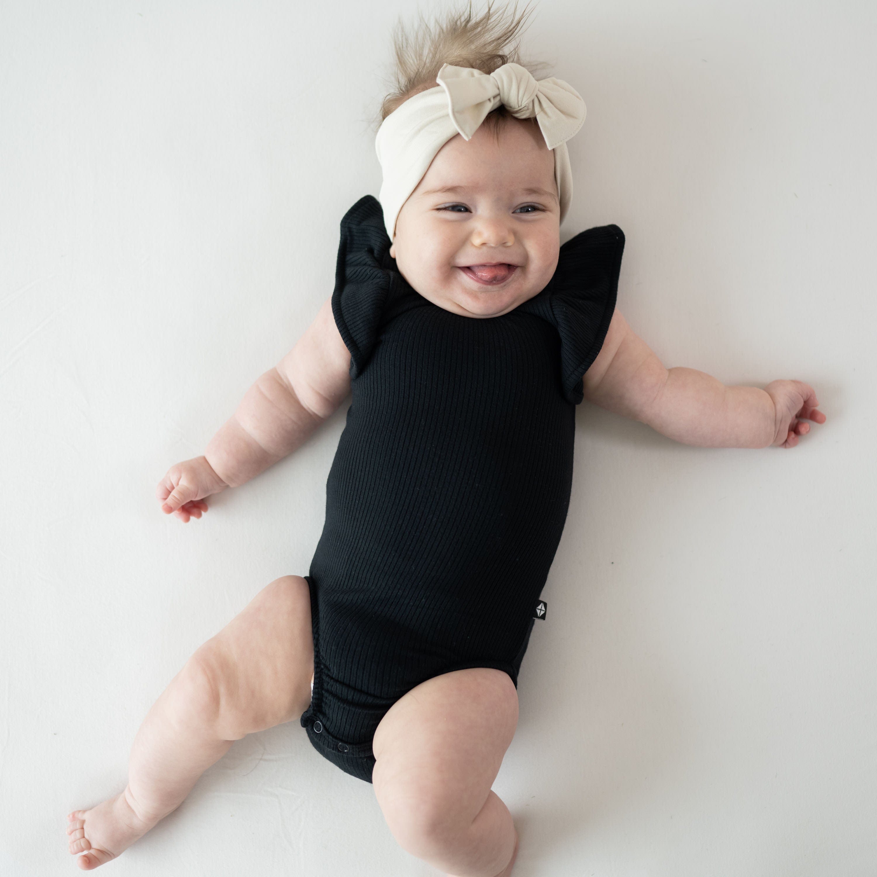 Infant wearing Kyte Baby Ribbed Sleeveless Ruffle Leotard in Midnight