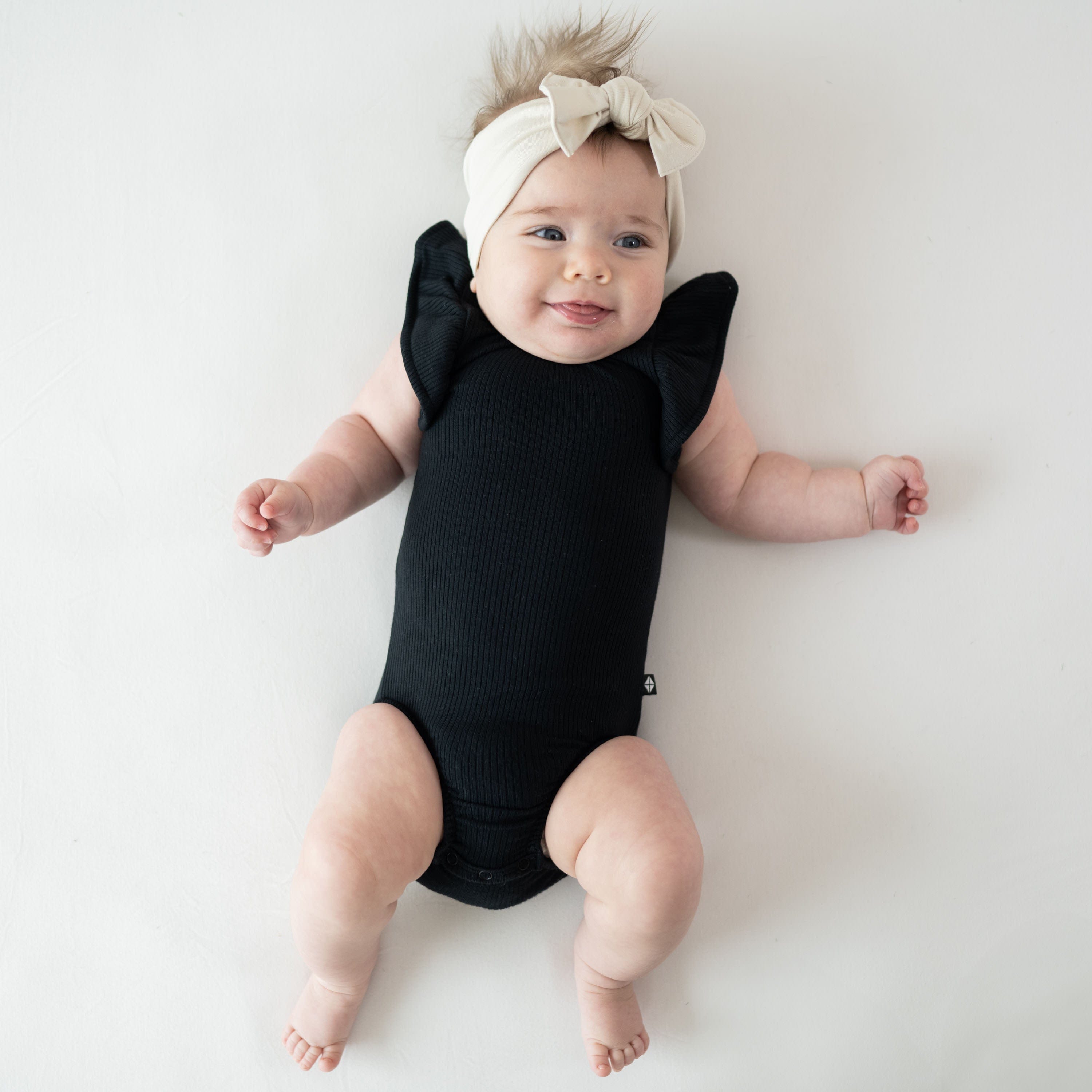 Infant wearing Kyte Baby bamboo Ribbed Sleeveless Ruffle Leotard in Midnight