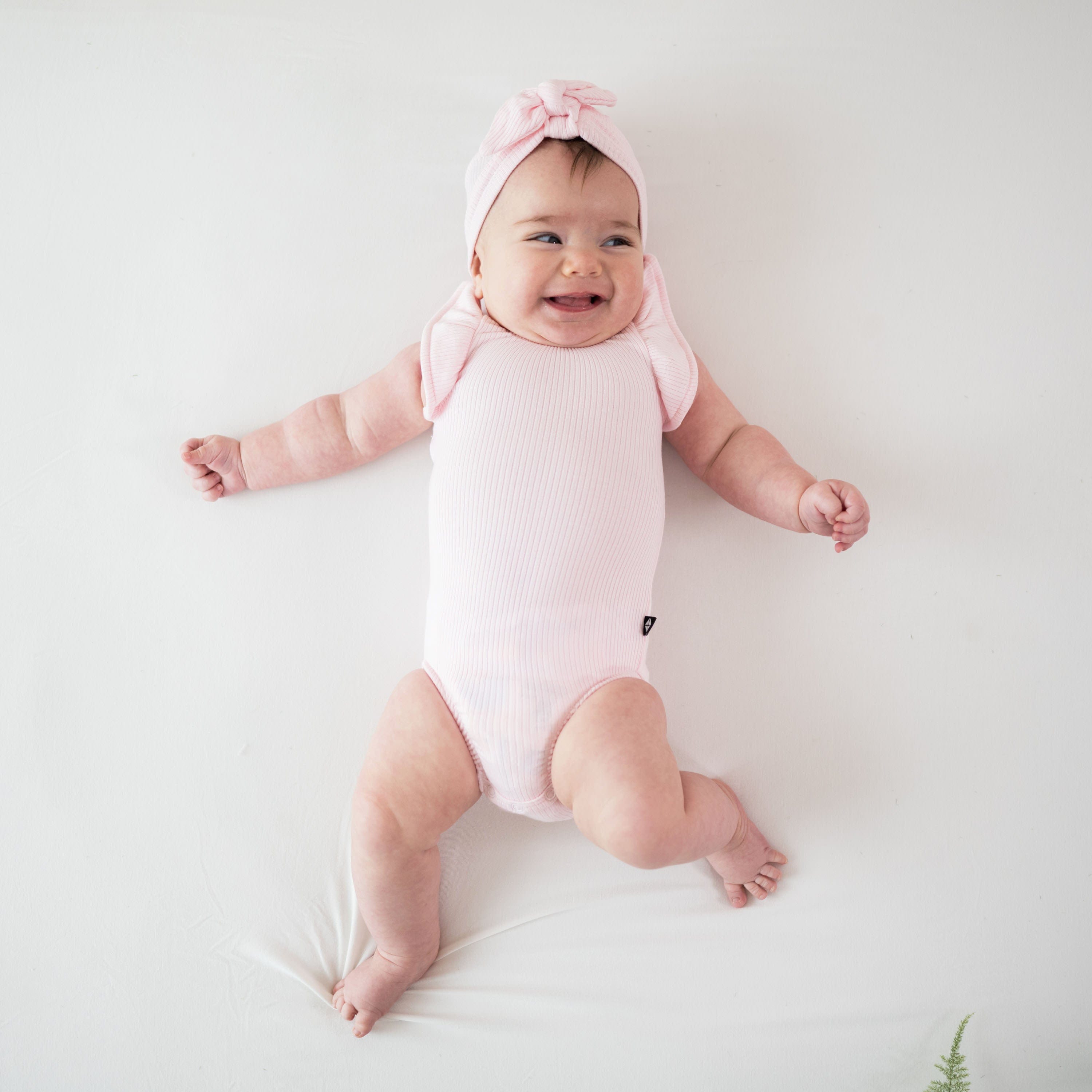 Infant wearing Kyte Baby bamboo Ribbed Sleeveless Ruffle Leotard in Sakura