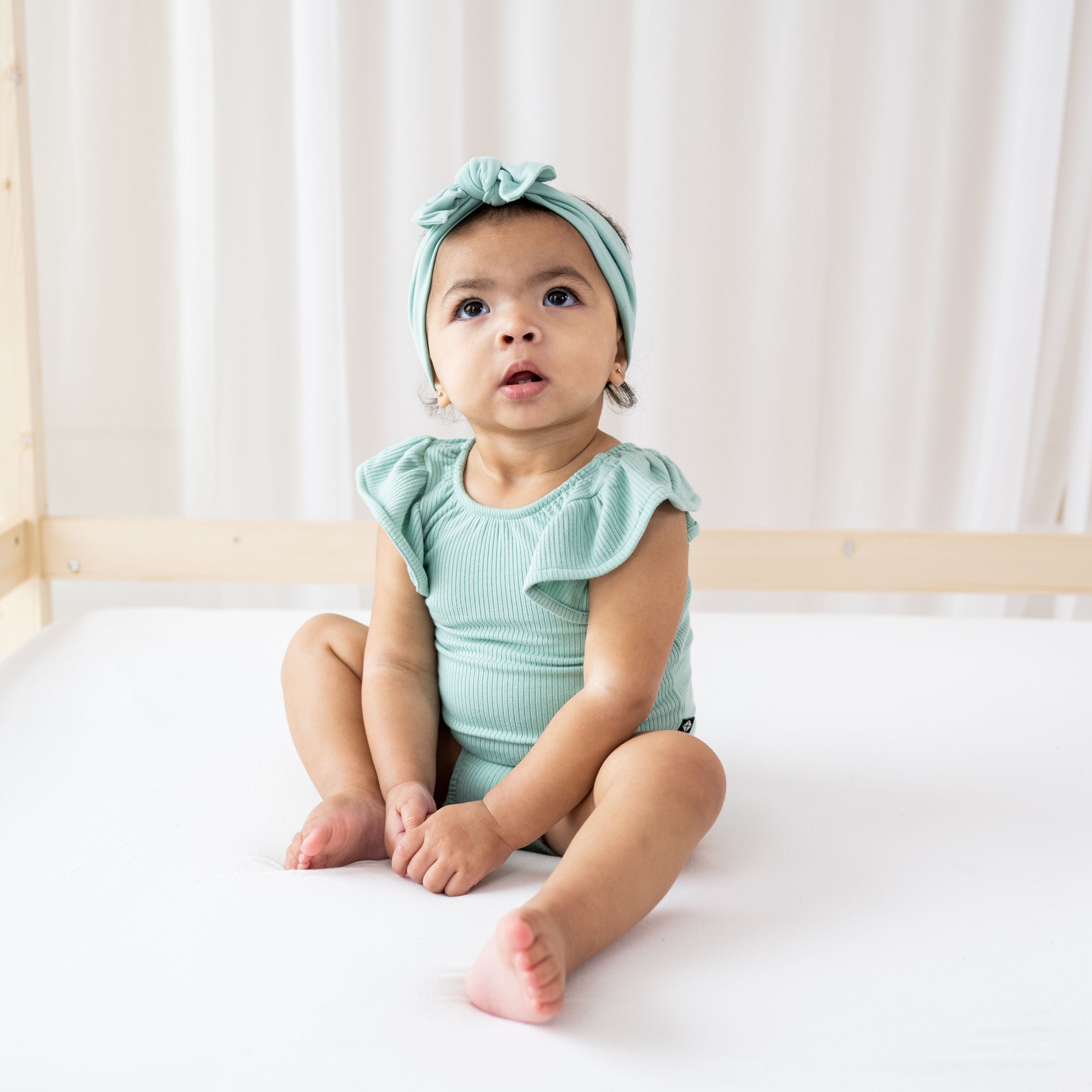 Infant wearing Kyte Baby bamboo Ribbed Sleeveless Ruffle Leotard in Wasabi