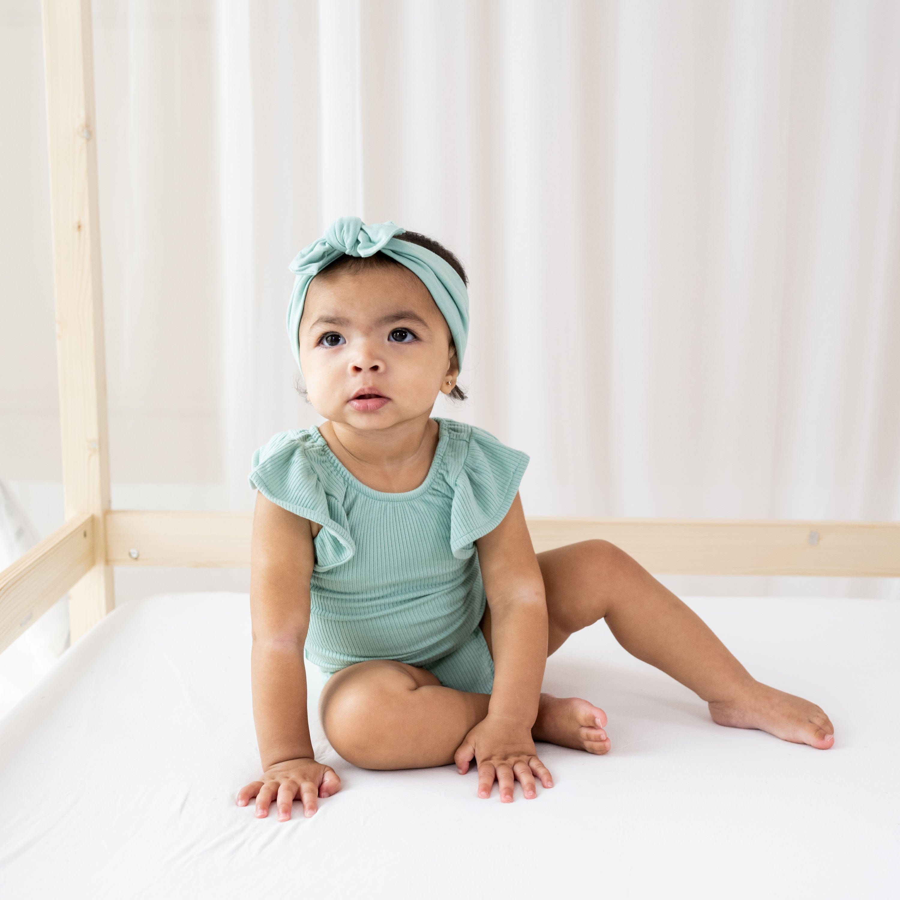 Infant wearing Kyte Baby Ribbed Sleeveless Ruffle Leotard in Wasabi