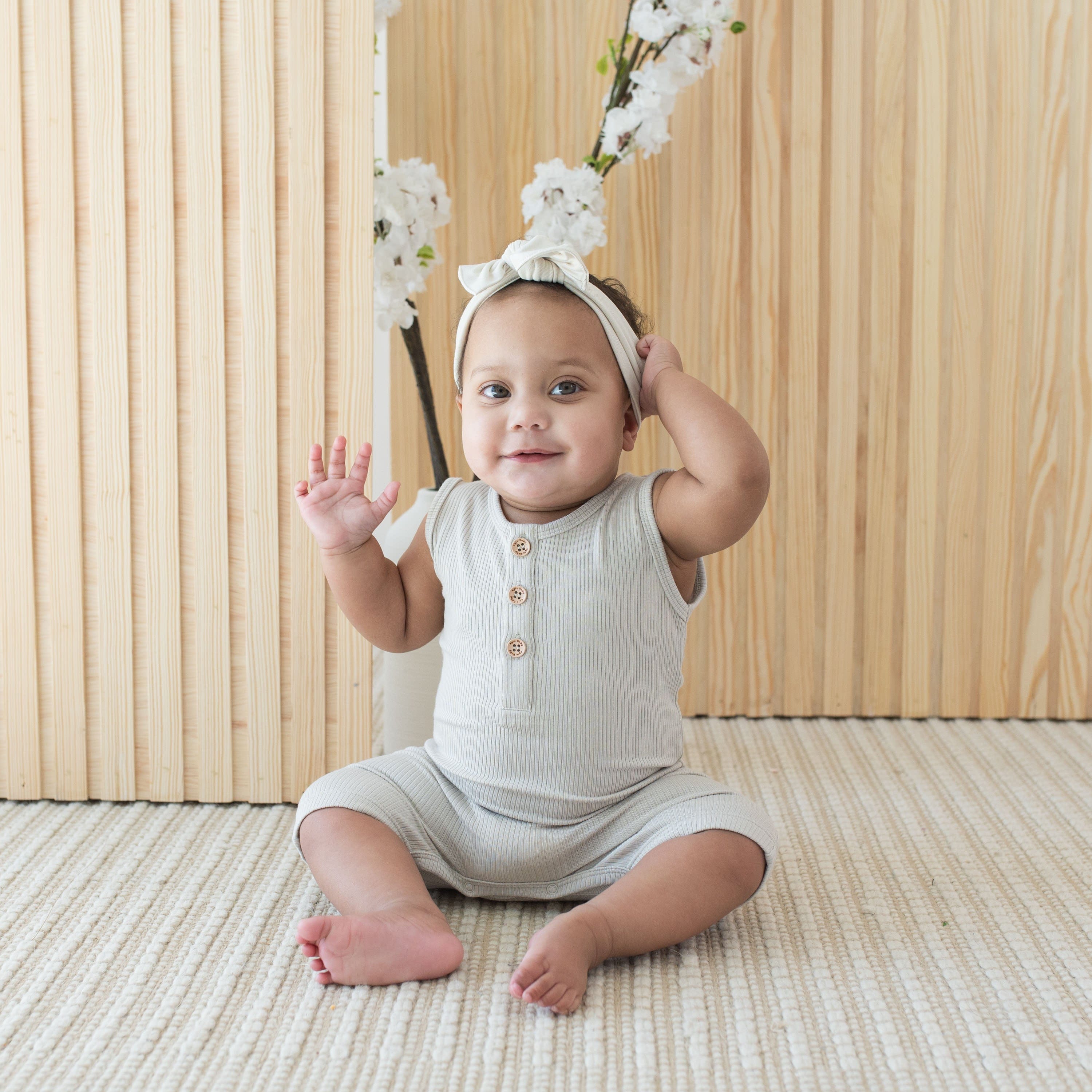 Infant wearing Kyte Baby Ribbed Sleeveless Shortall in Oat