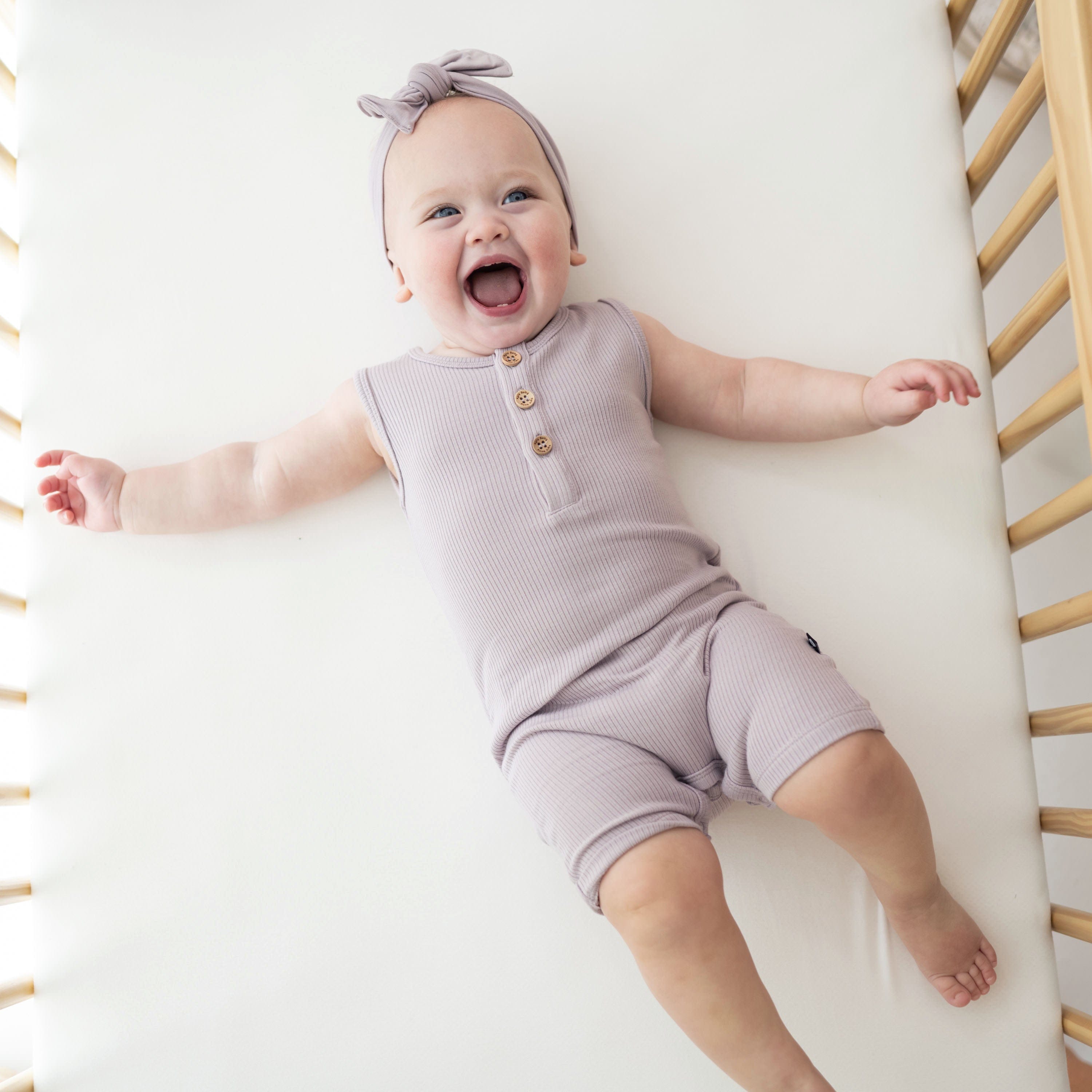 Infant wearing Kyte Baby Ribbed Sleeveless Shortall in Wisteria