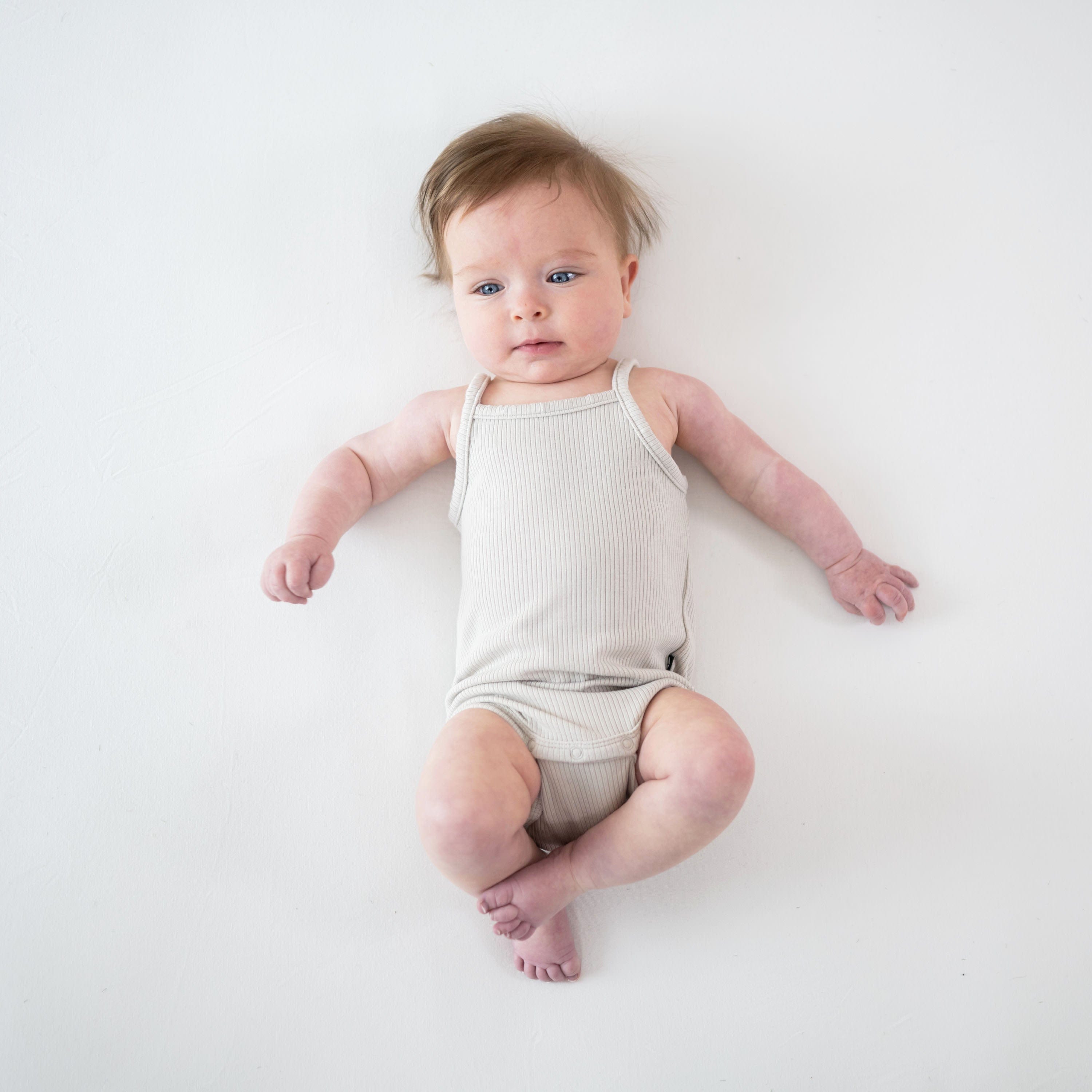 Infant wearing Kyte Baby Ribbed Spaghetti Strap Bodysuit in Oat