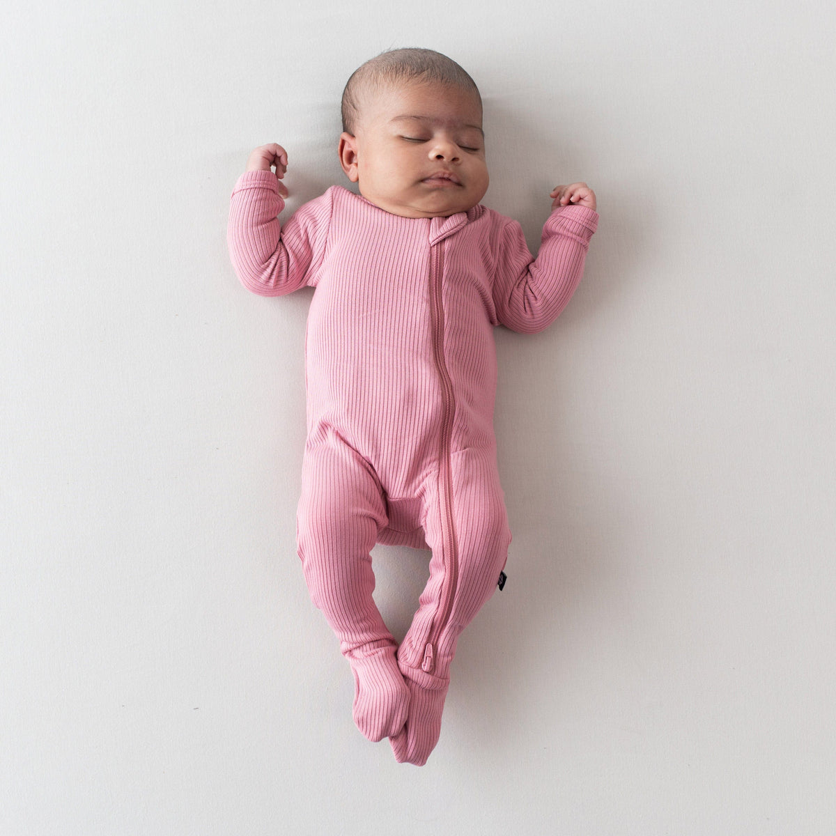 Newborn wearing Ribbed Zipper Footie in Apple Blossom pink