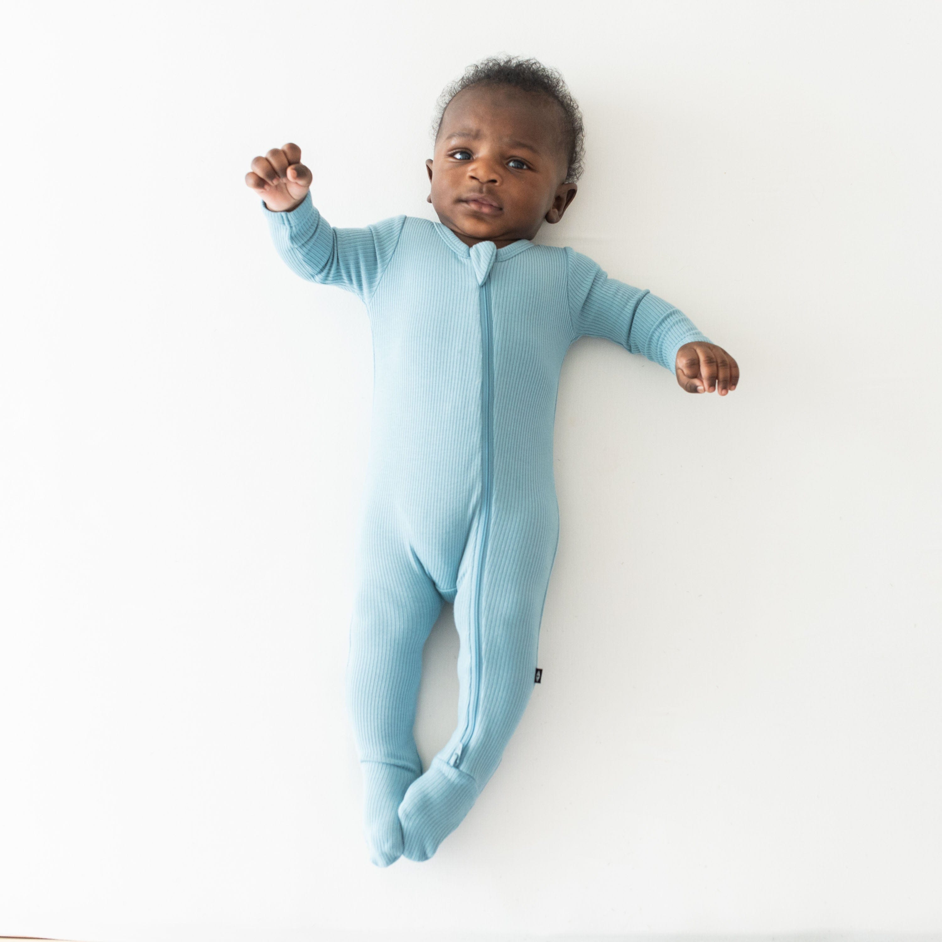 Infant wearing Kyte Baby Ribbed Zipper Footie in Dusty Blue