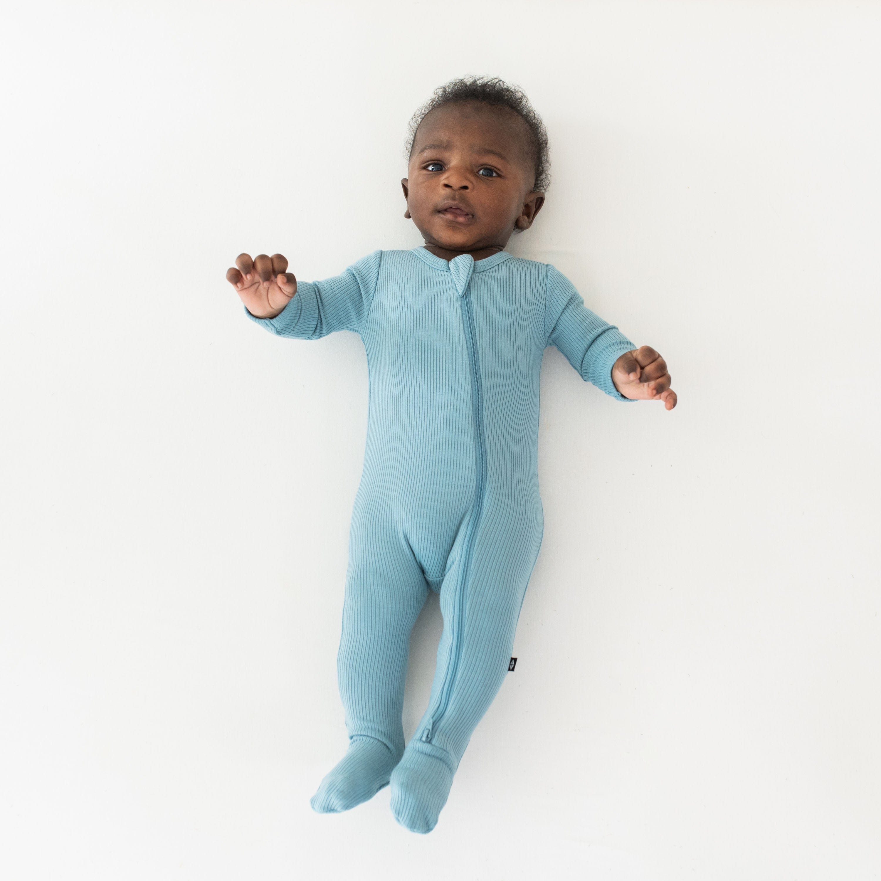 Child wearing Kyte Baby bamboo Ribbed Zipper Footie in Dusty Blue