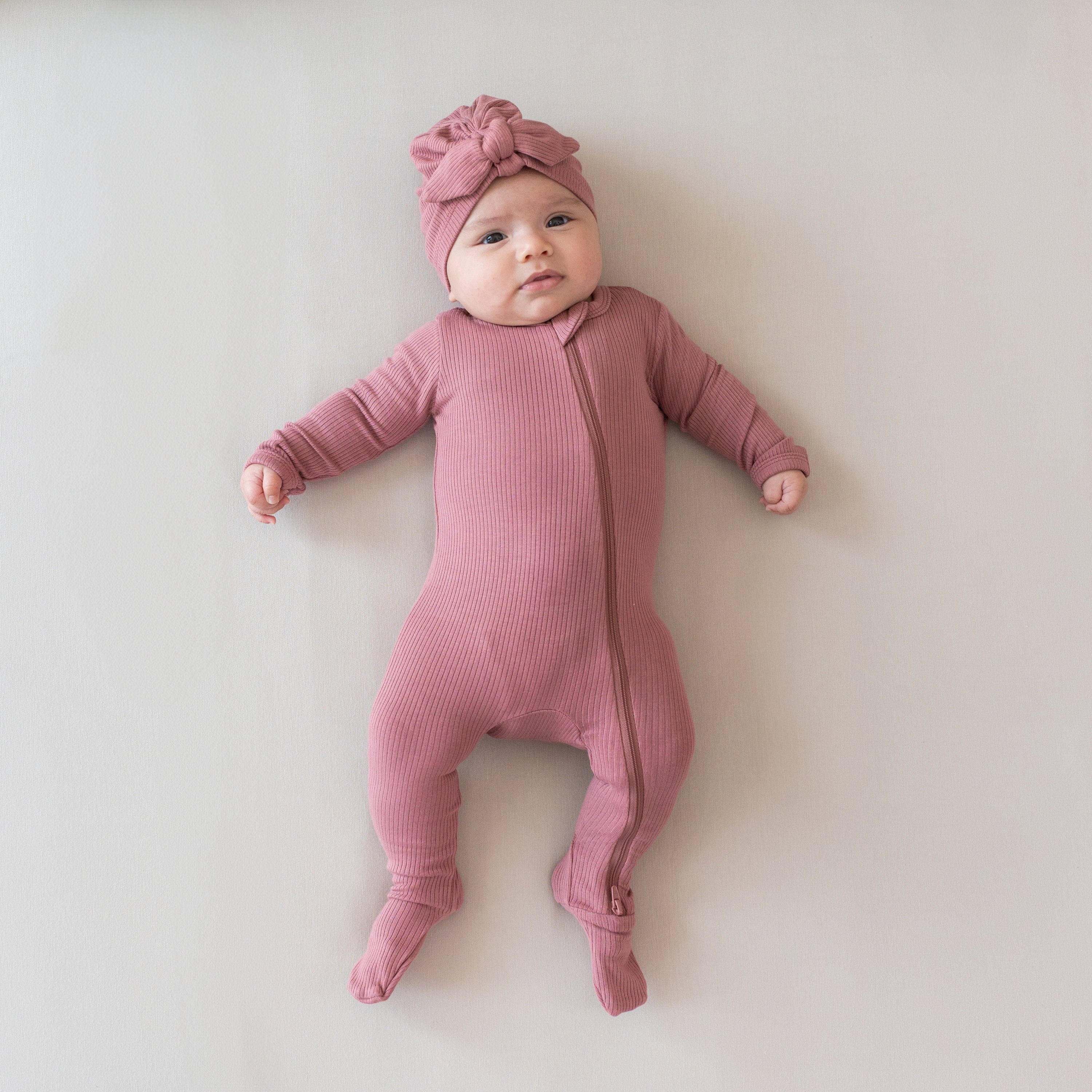 Infant wearing Kyte Baby Ribbed Zippered Footie in Dusty Rose