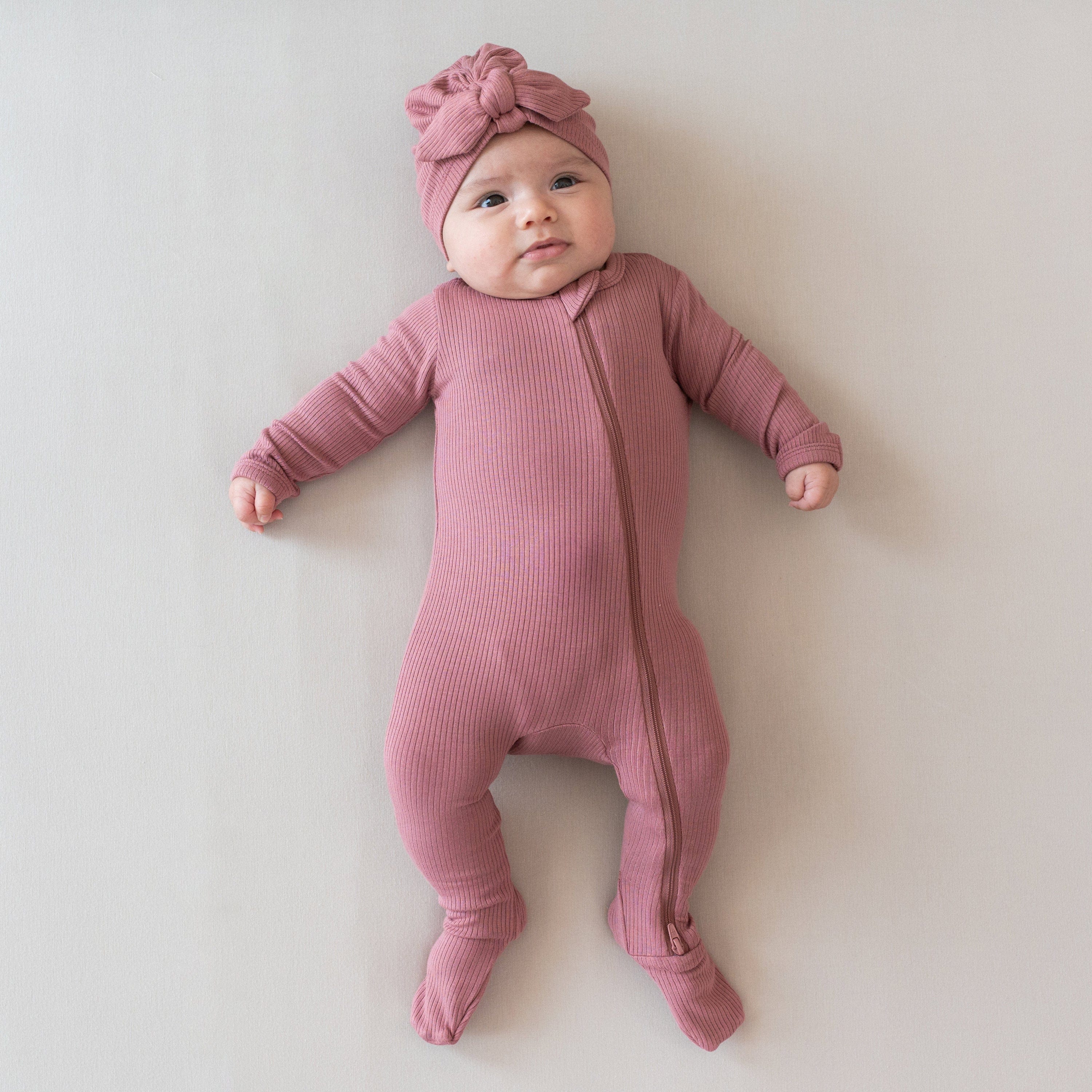 Infant wearing Kyte Baby bamboo Ribbed Zippered Romper in Dusty Rose