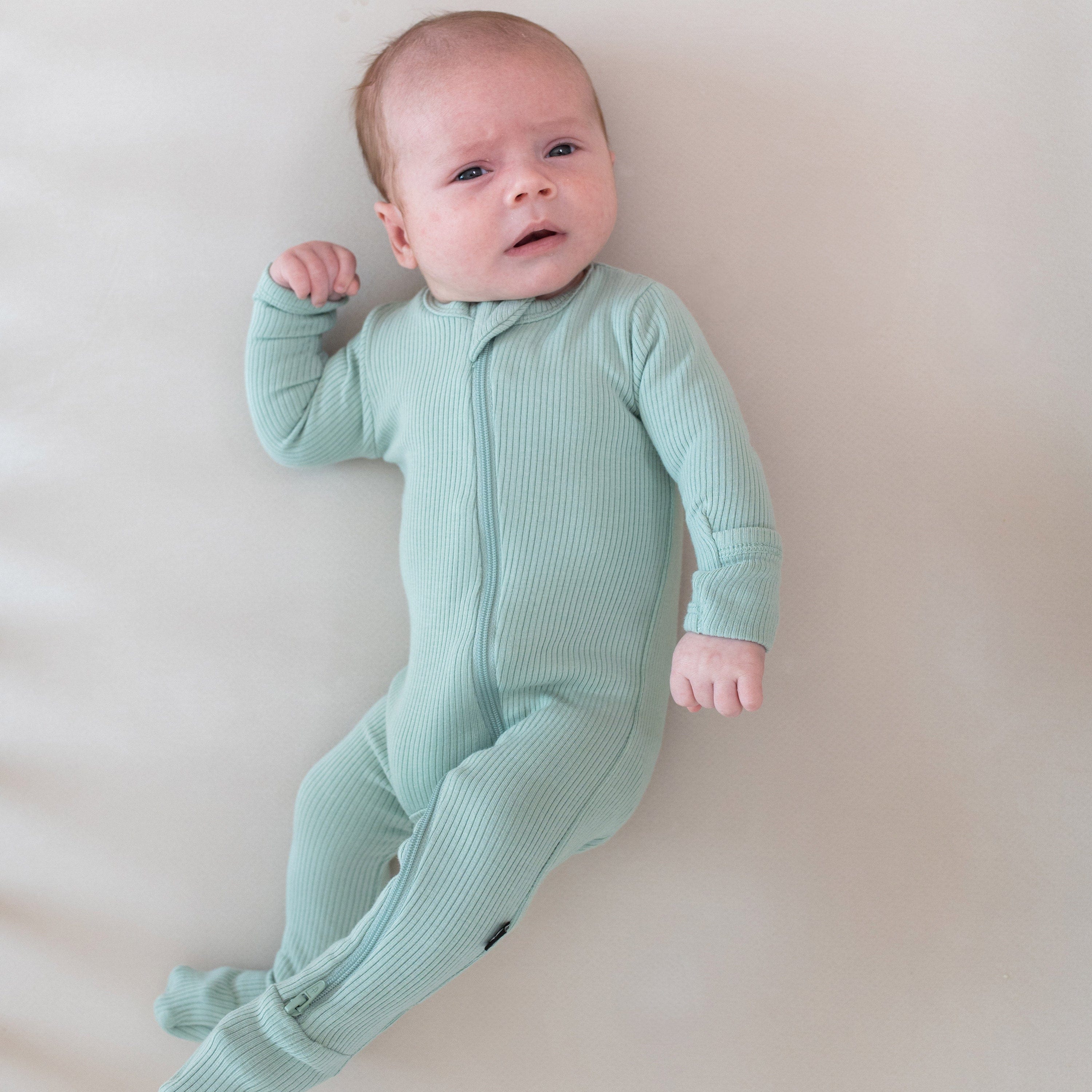 Baby wearing Kyte Baby Ribbed Zippered Footie in Sage