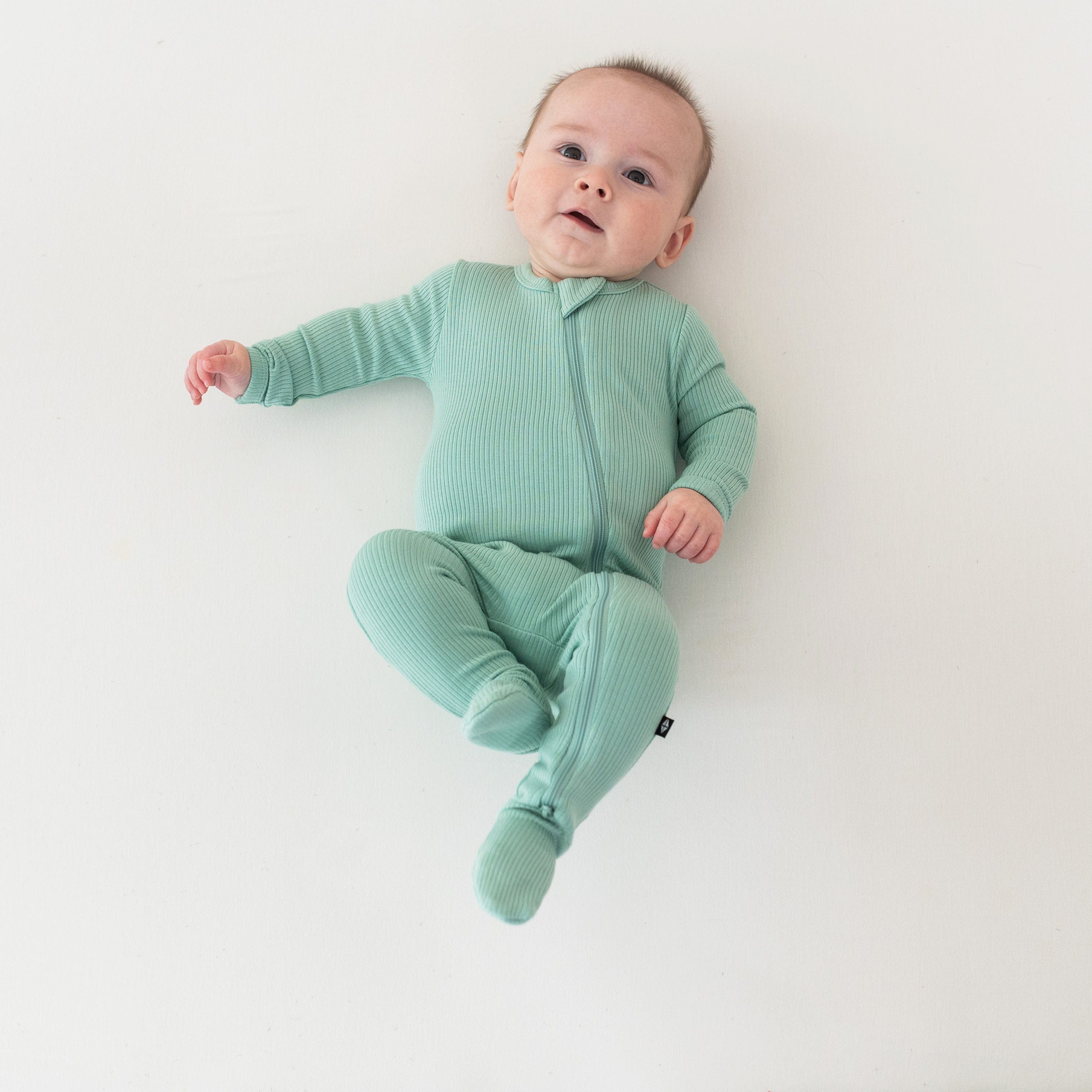 Child wearing Kyte Baby Ribbed Zipper Footie pajamas in Wasabi