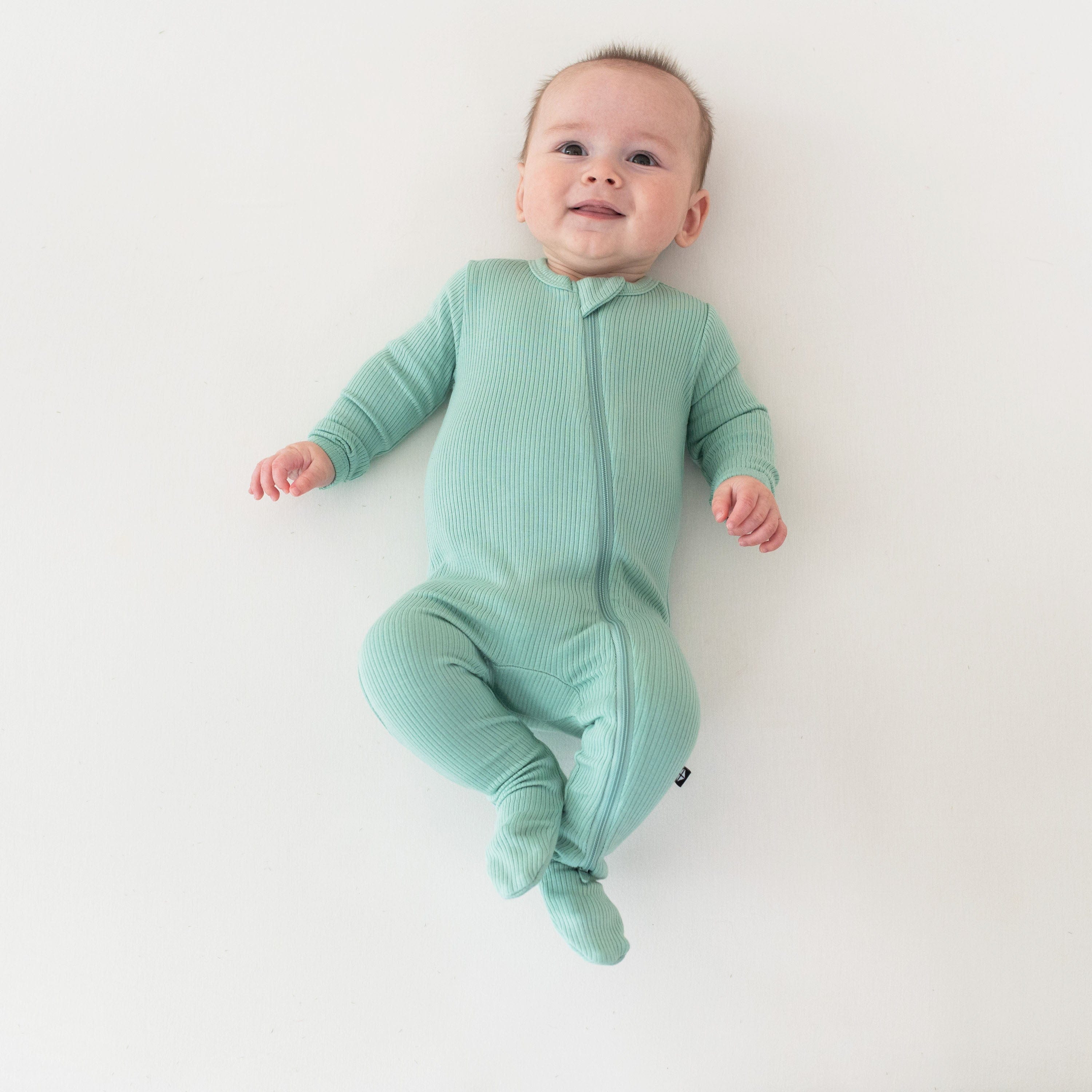 Infant wearing Kyte Baby Ribbed Zipper Footie in Wasabi