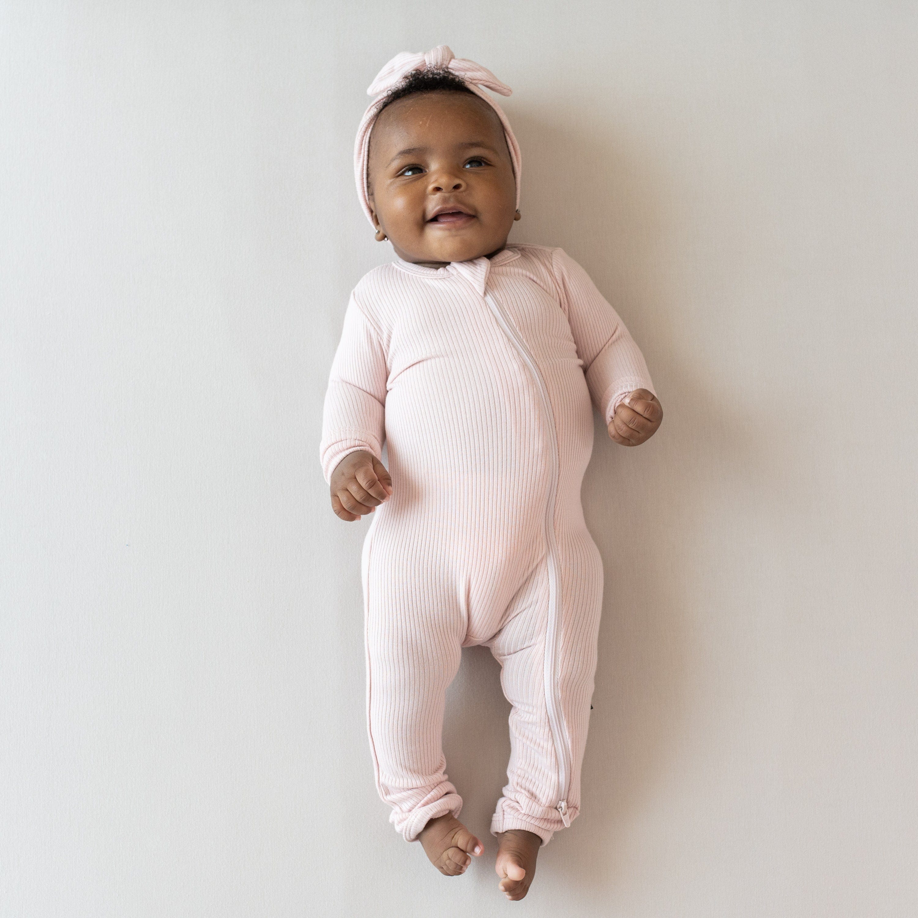 Infant wearing Kyte Baby Ribbed Zippered Romper in Blush