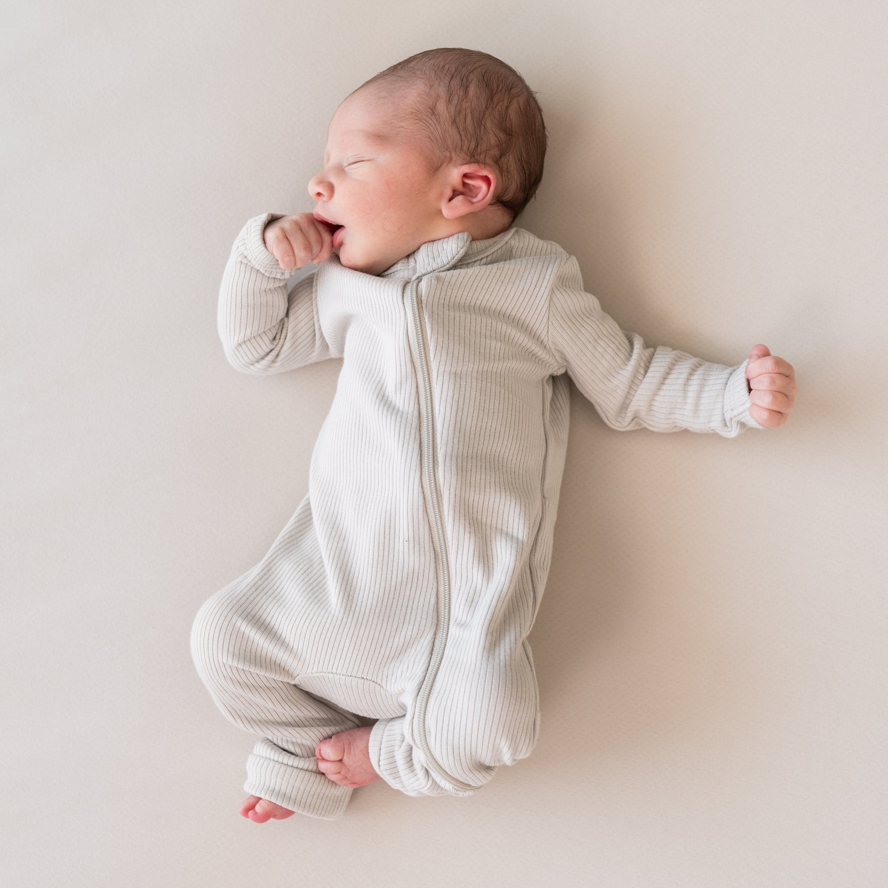 Infant wearing Kyte Baby Ribbed Zippered Romper in Oat