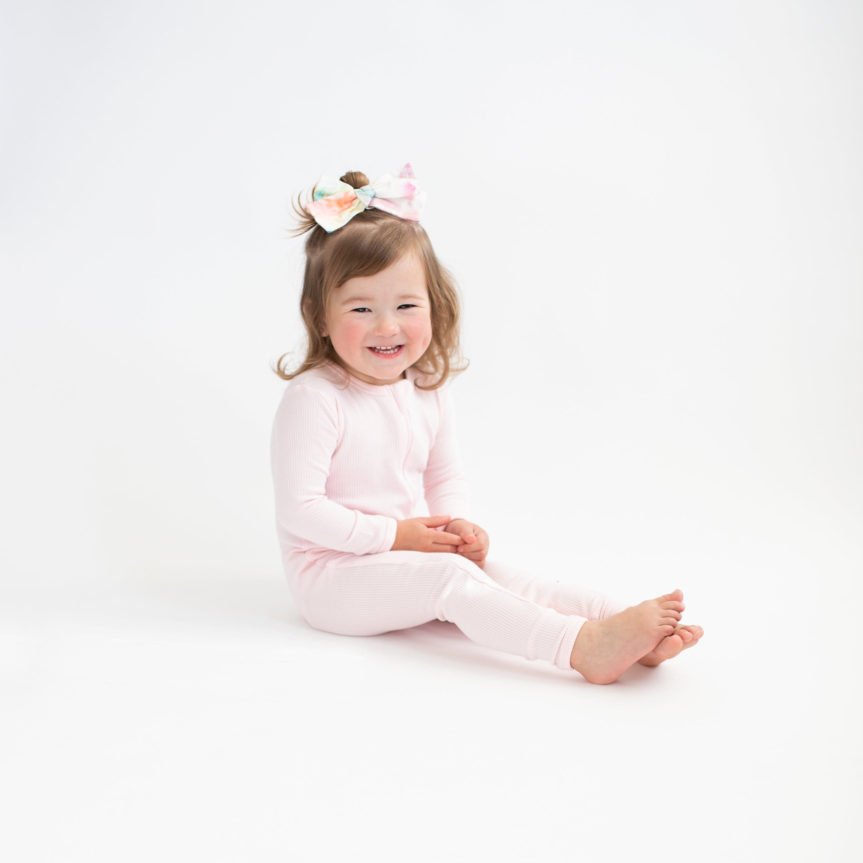 Toddler wearing Kyte Baby Ribbed Zippered Romper pajamas in Sakura