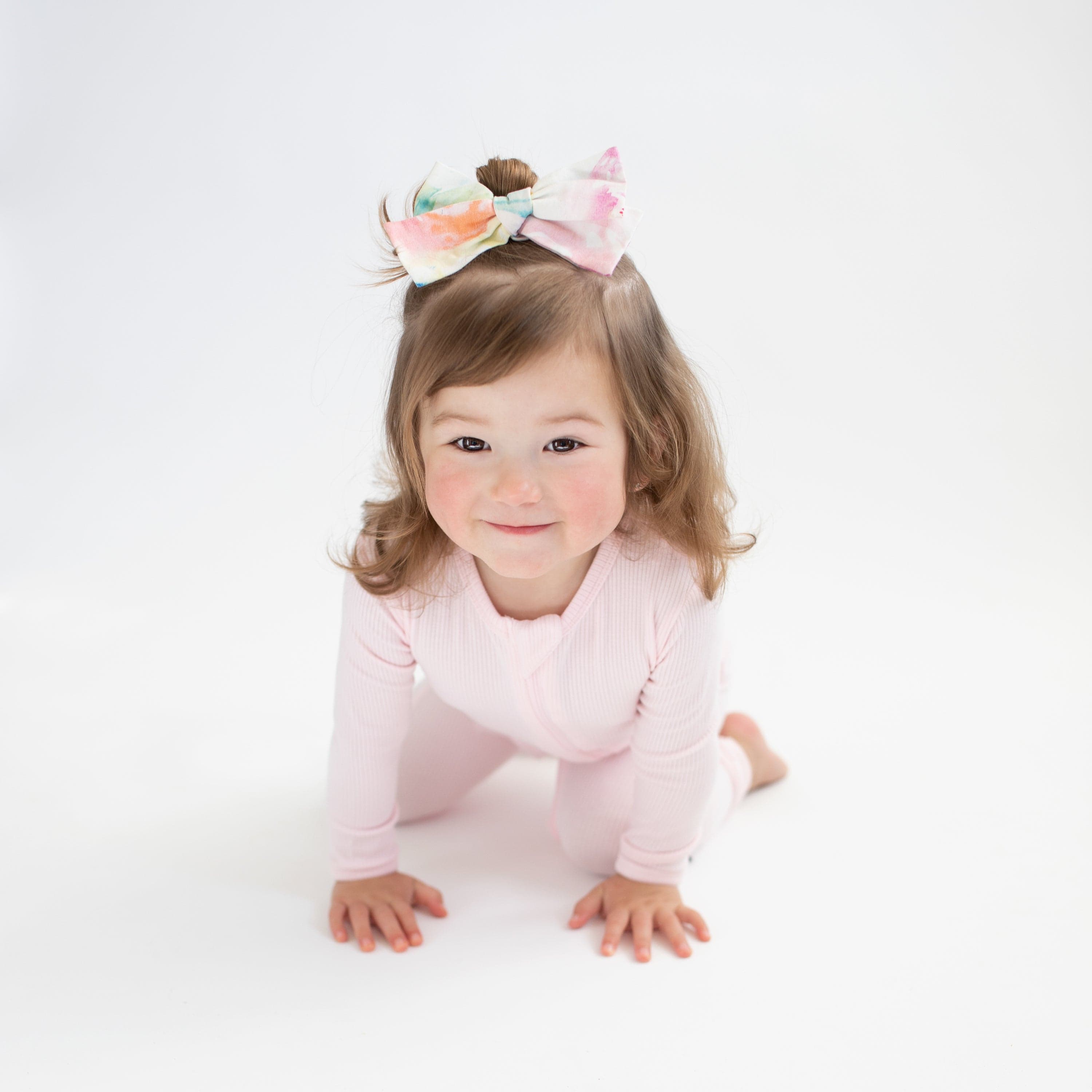 Toddler wearing Kyte Baby Ribbed Zippered Romper in Sakura pink