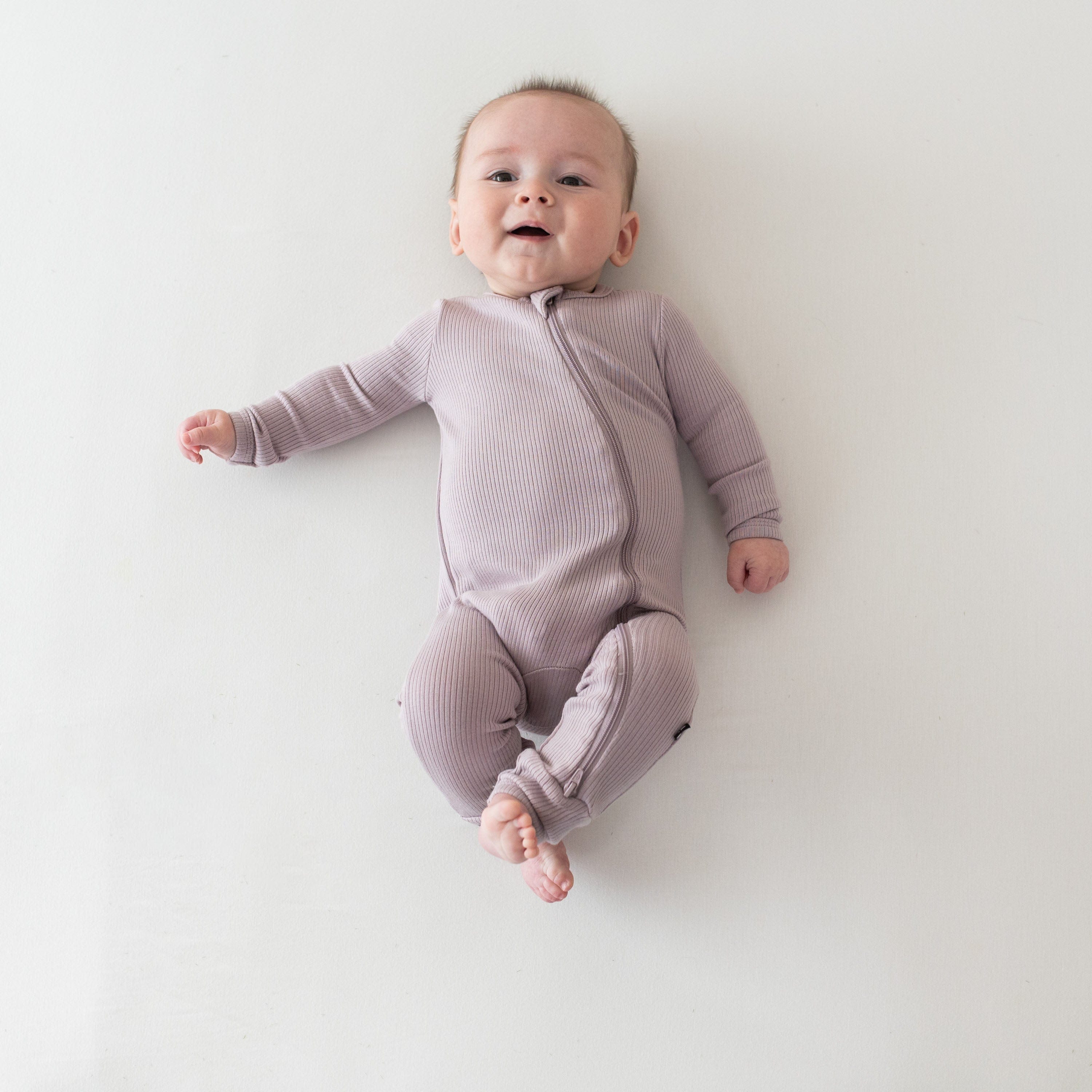 Infant wearing Kyte Baby bamboo Ribbed Zippered Romper in Wisteria
