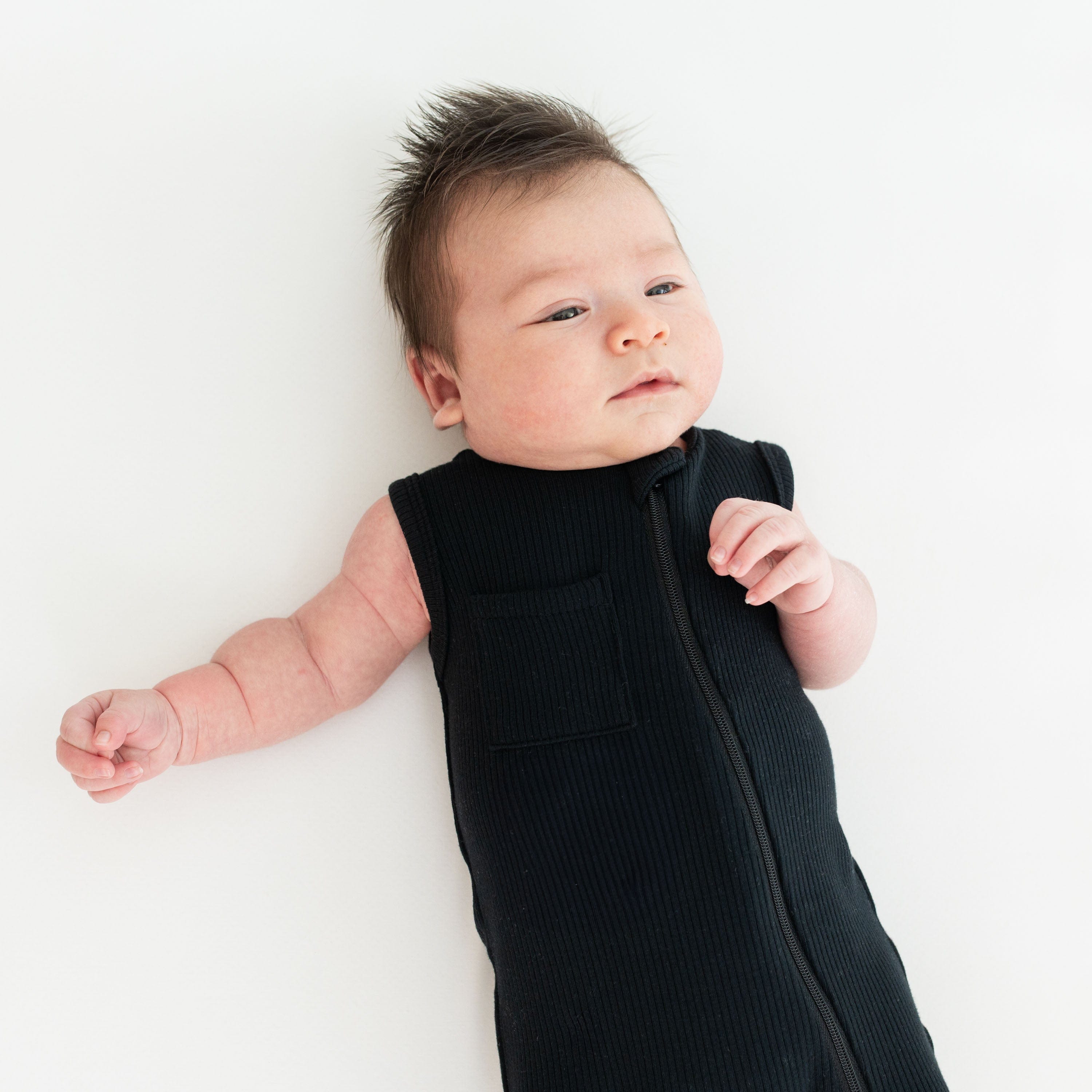 Baby wearing Kyte Baby Sleeveless Zippered Romper in Midnight black