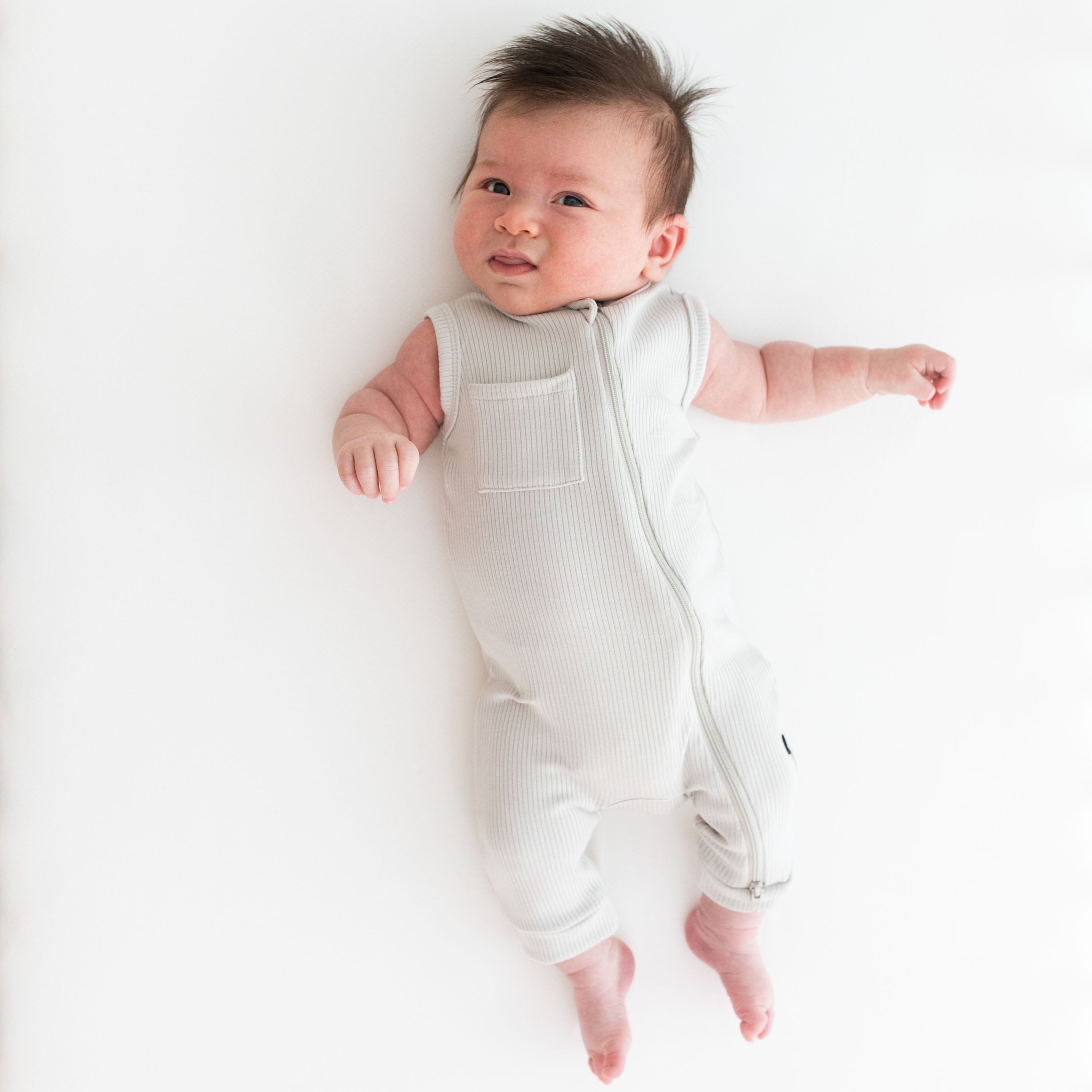 Infant wearing Kyte Baby Ribbed Zippered Sleeveless Romper in Oat