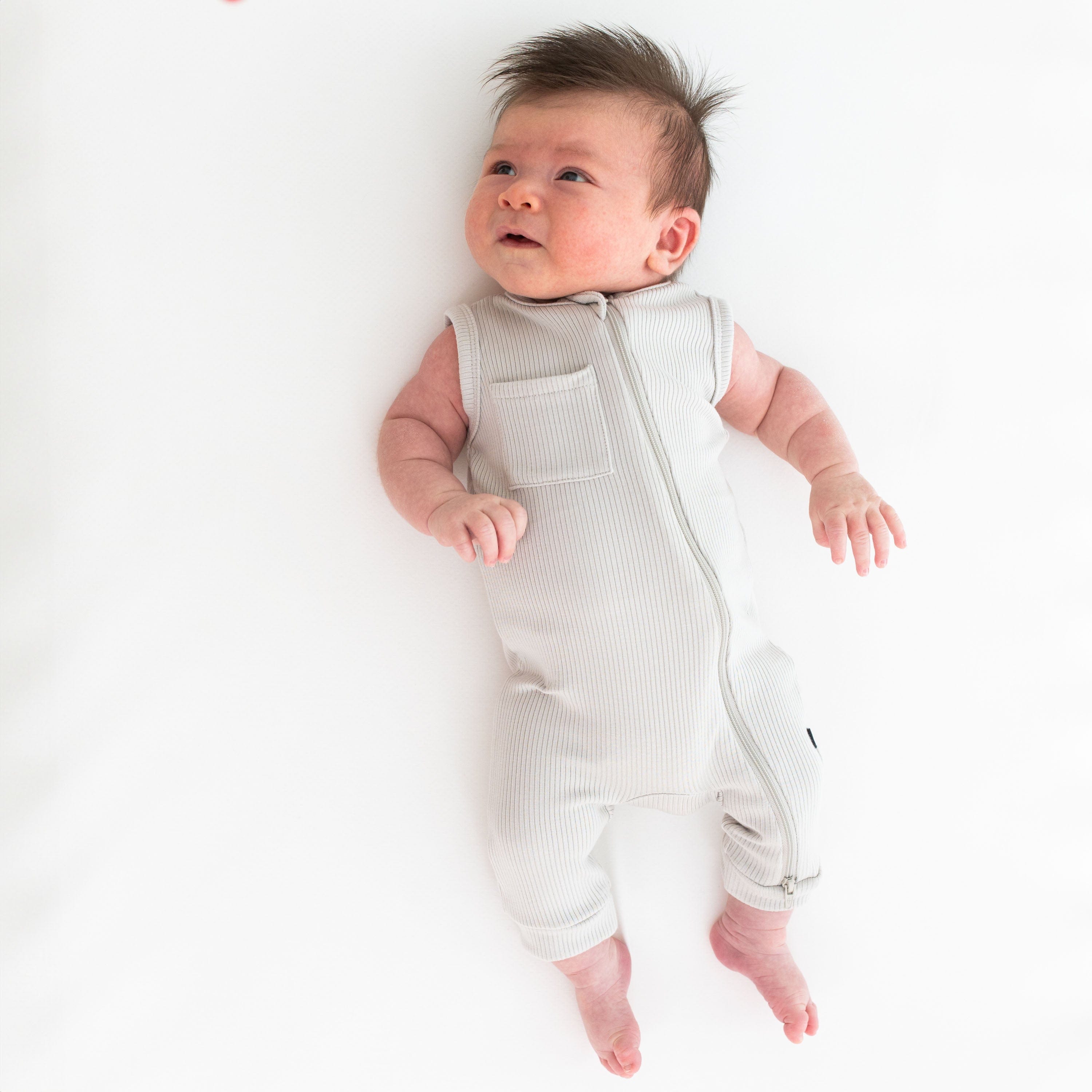Newborn wearing Kyte Baby bamboo Ribbed Zippered Sleeveless Romper in Oat