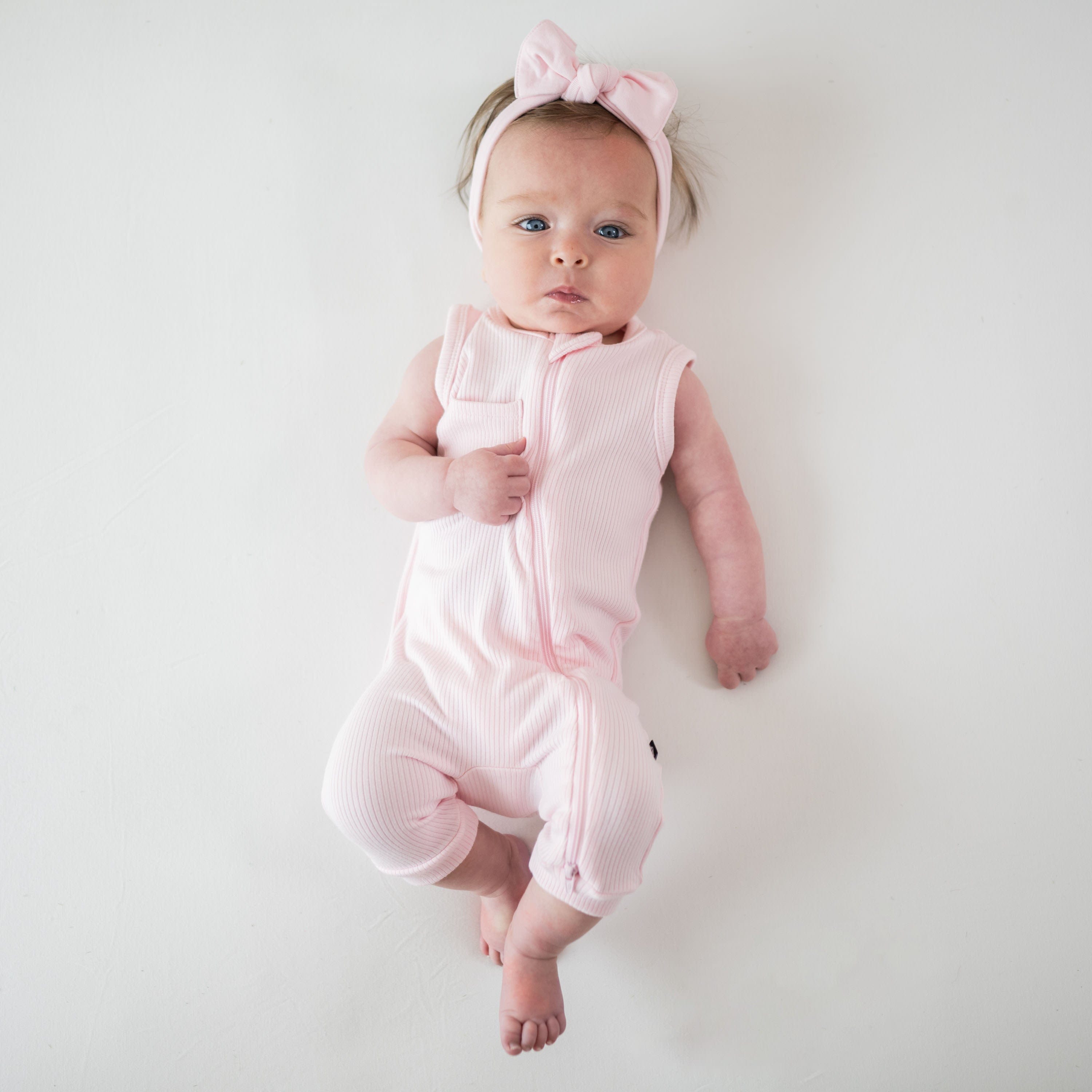 Newborn wearing Kyte Baby bamboo Ribbed Zippered Sleeveless Romper in Sakura pink