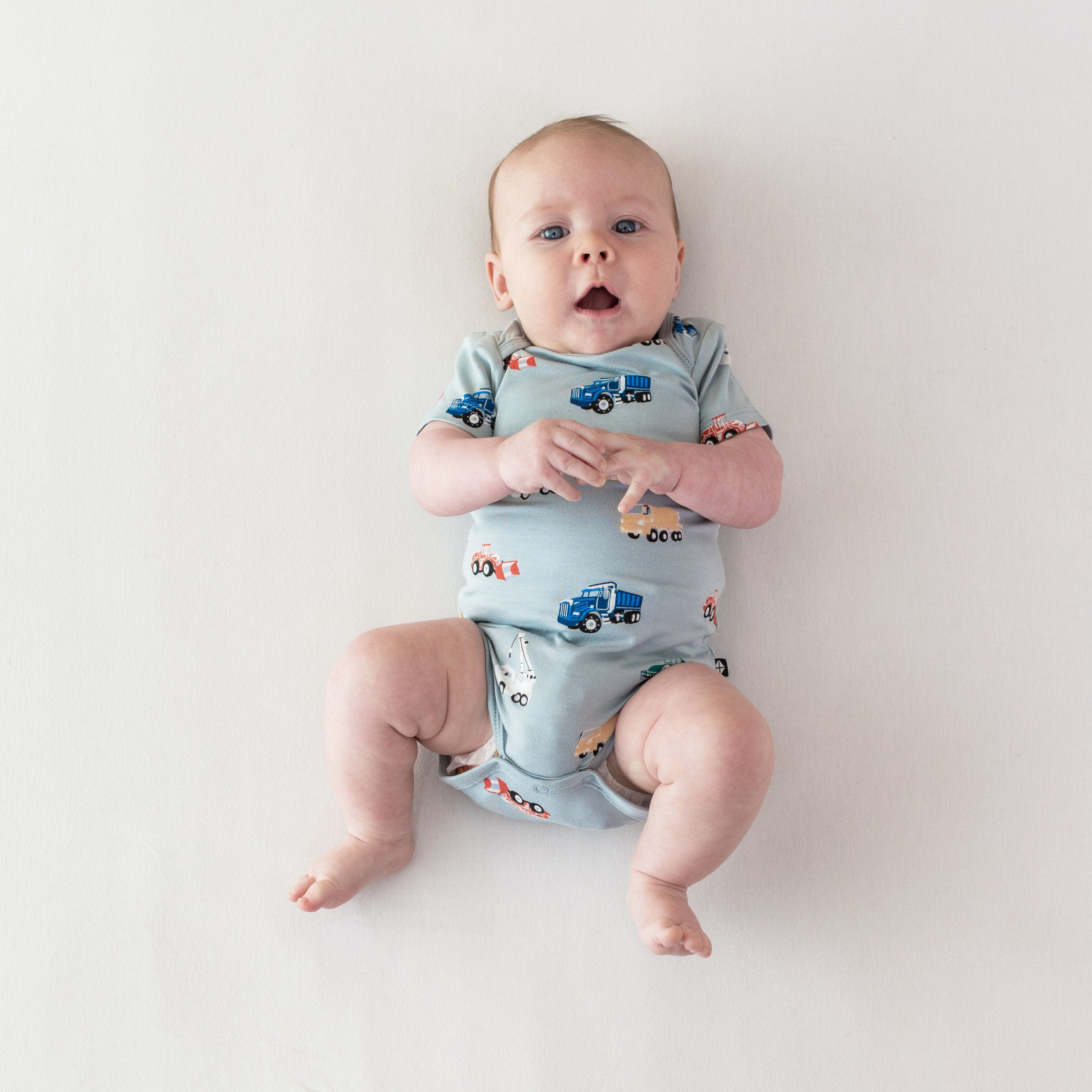 Infant wearing short sleeve Kyte Baby Bodysuit in Construction