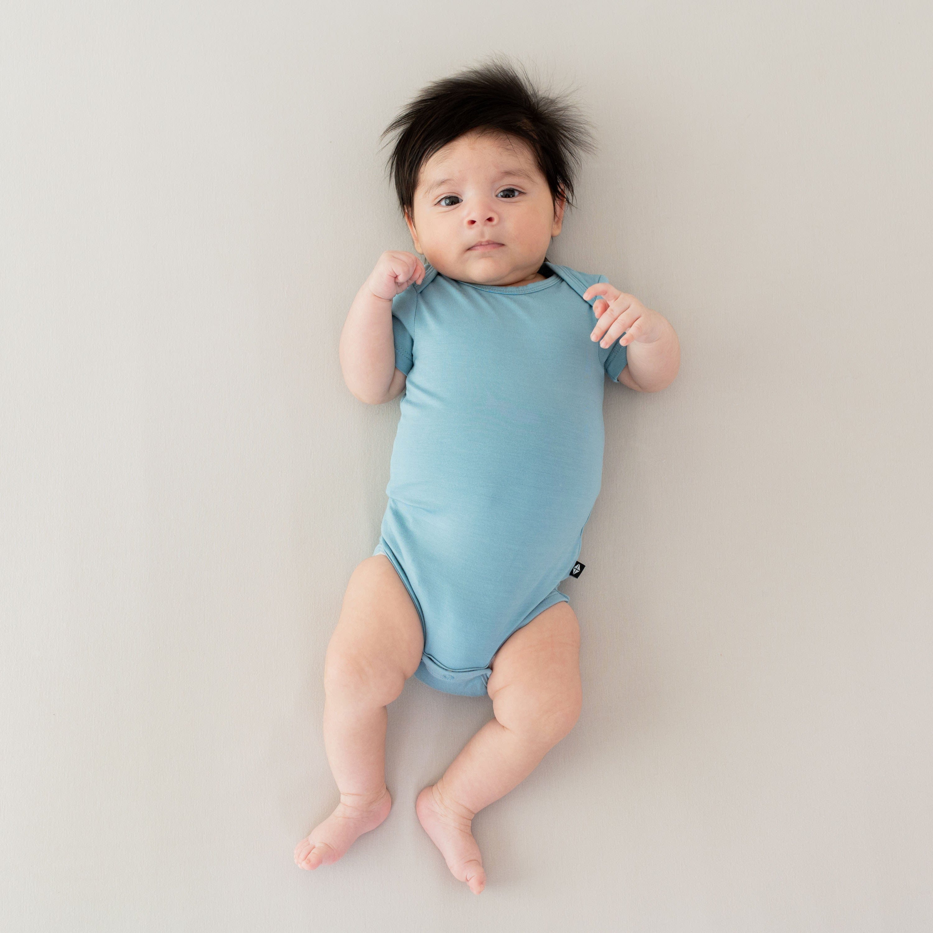 Newborn wearing Kyte Baby Bodysuit in Dusty Blue