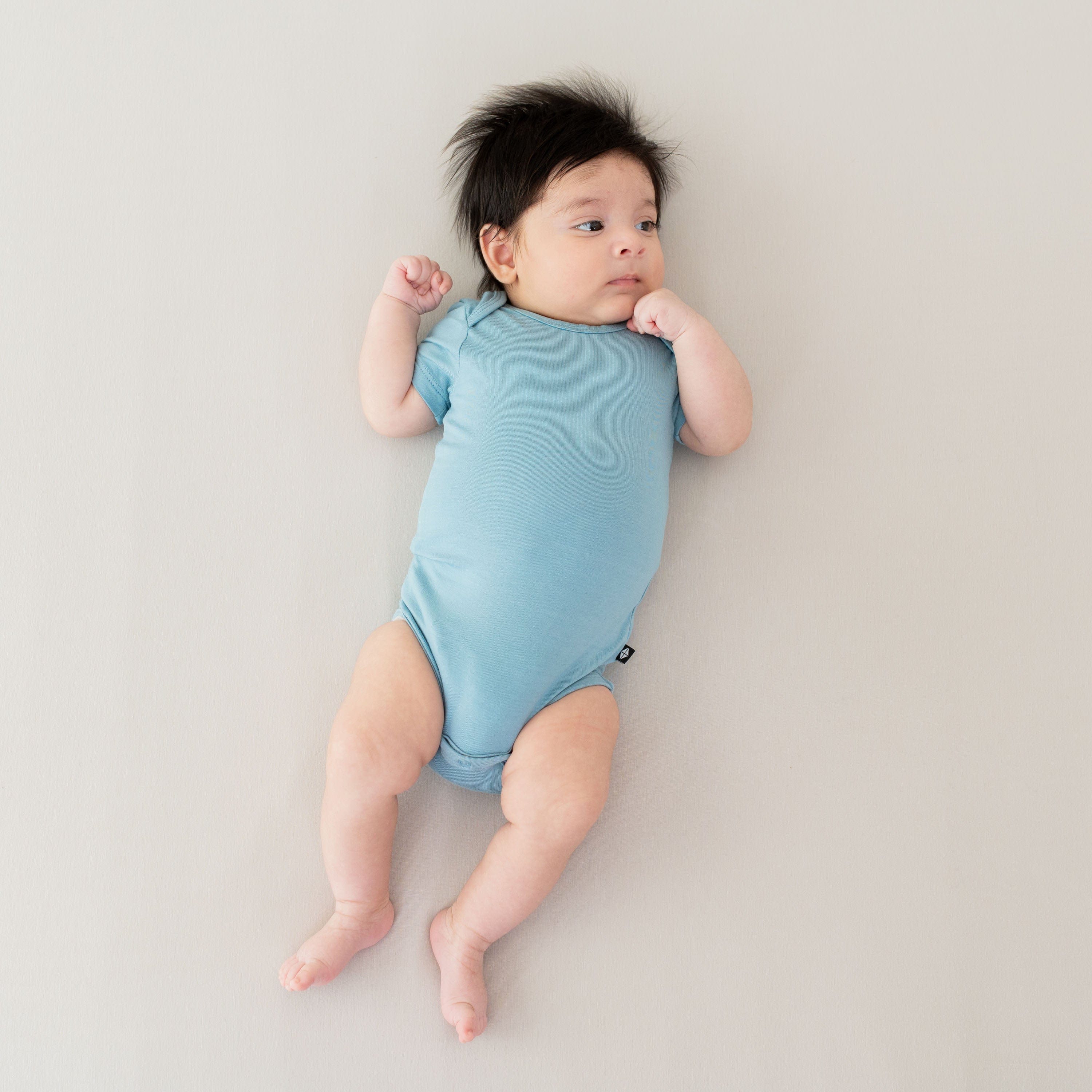 Baby wearing Kyte Baby infant Bodysuit in Dusty Blue