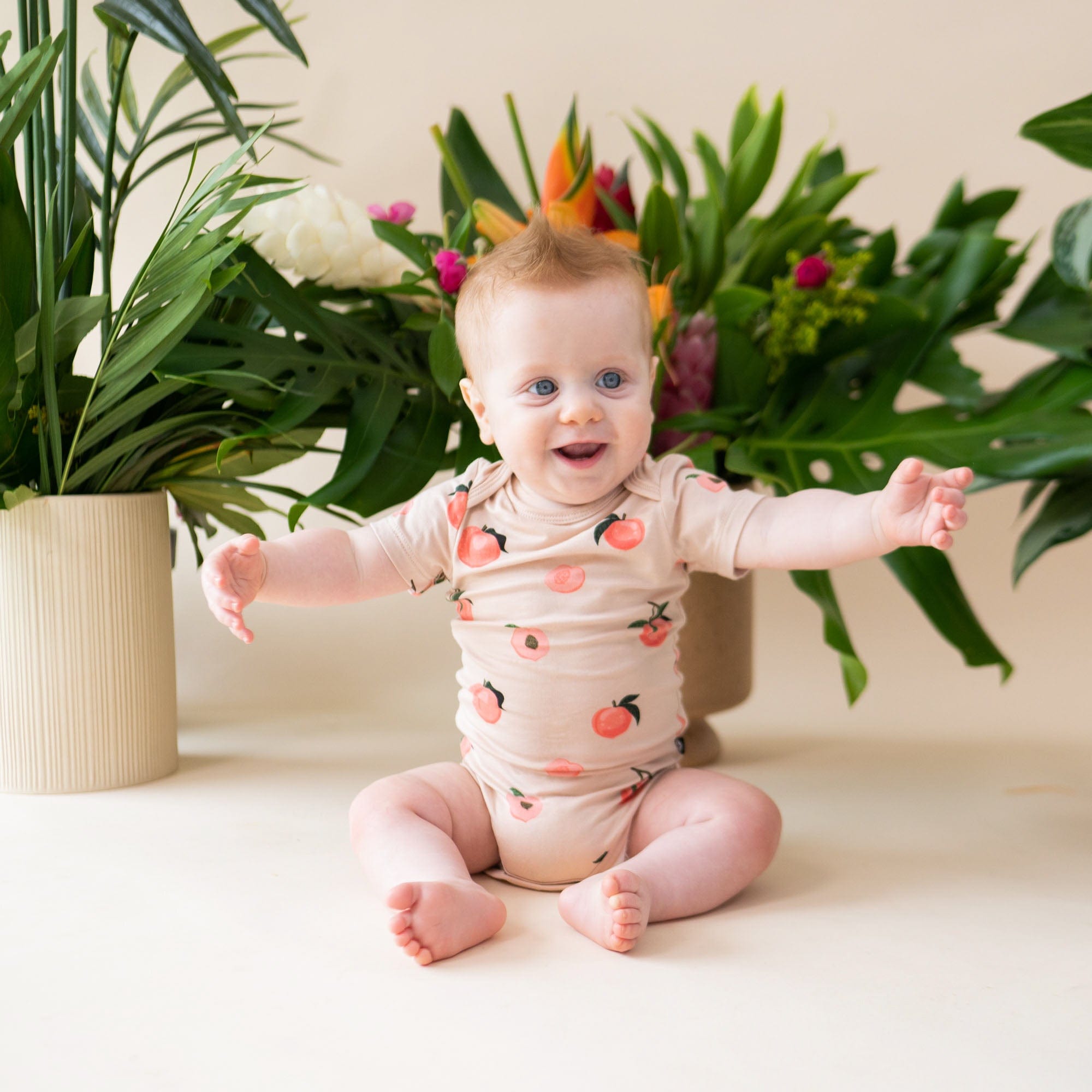 Infant wearing short sleeve Kyte Baby Bodysuit in Peach