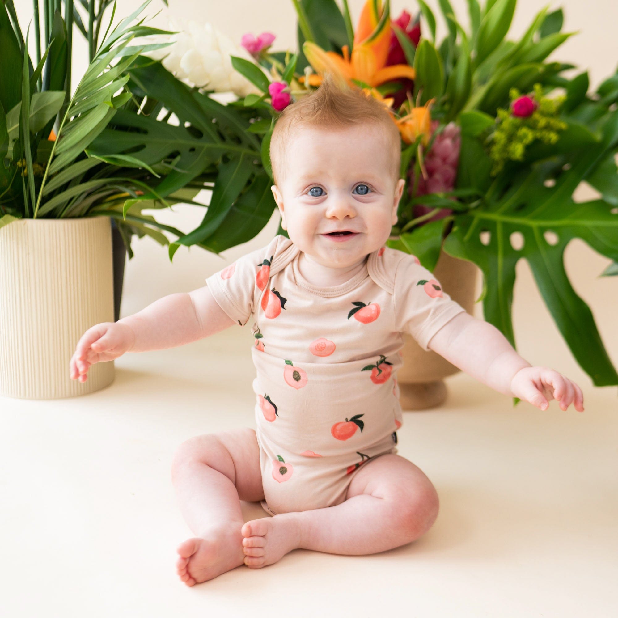 Baby wearing Kyte Baby infant Bodysuit in Peach