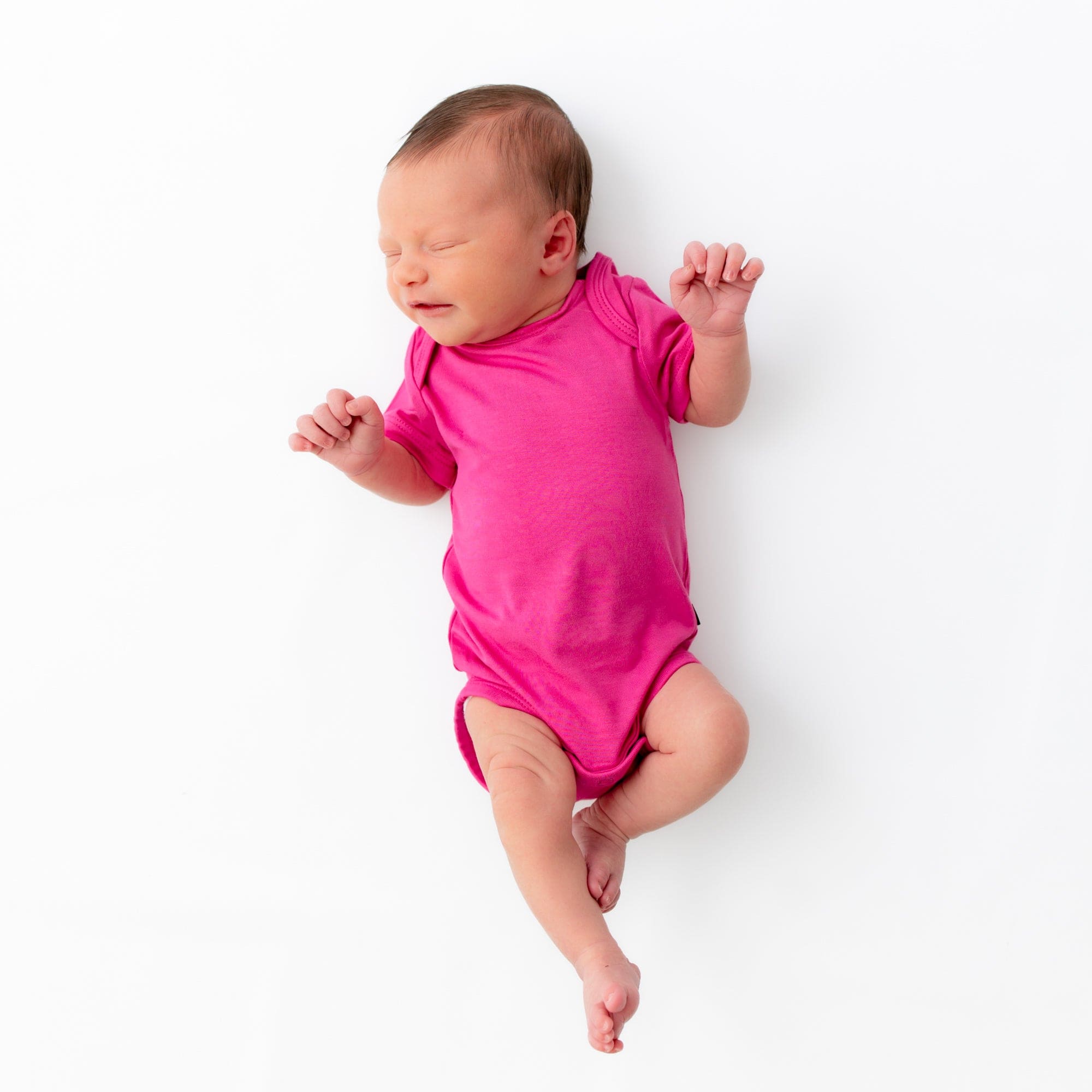Newborn wearing Kyte Baby Bodysuit in Raspberry