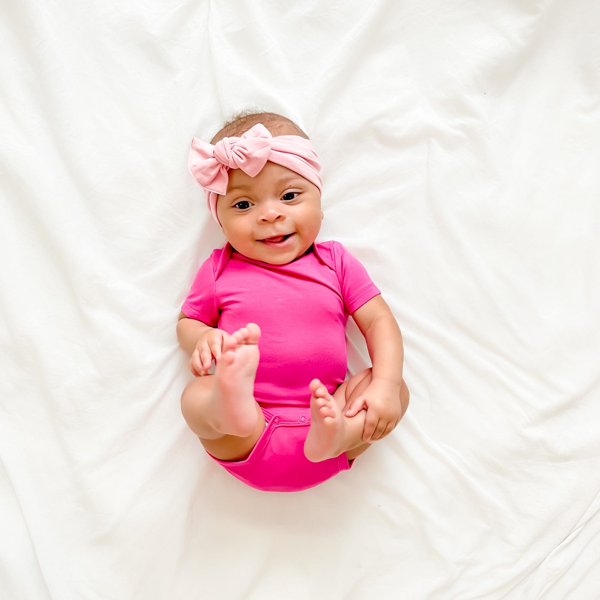 Infant wearing short sleeve Kyte Baby Bodysuit in Raspberry