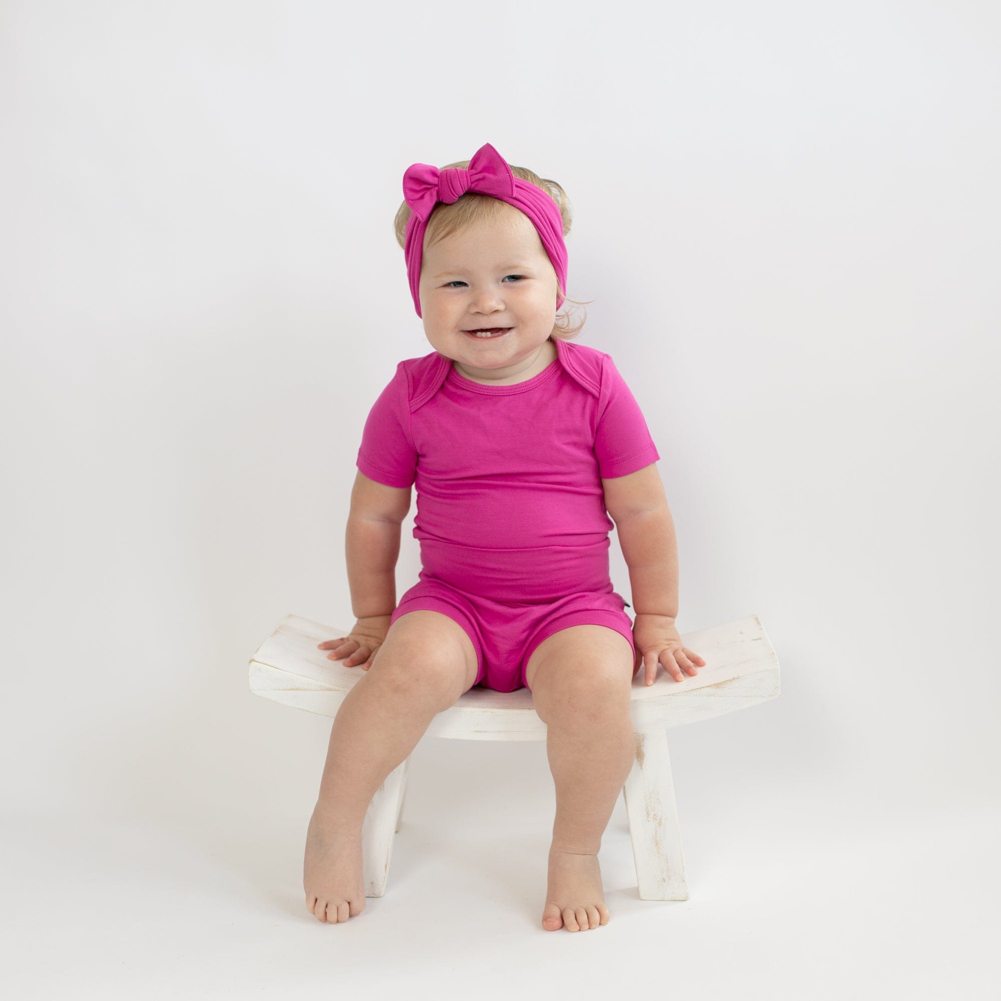 Child wearing Kyte Baby infant Bodysuit in Raspberry