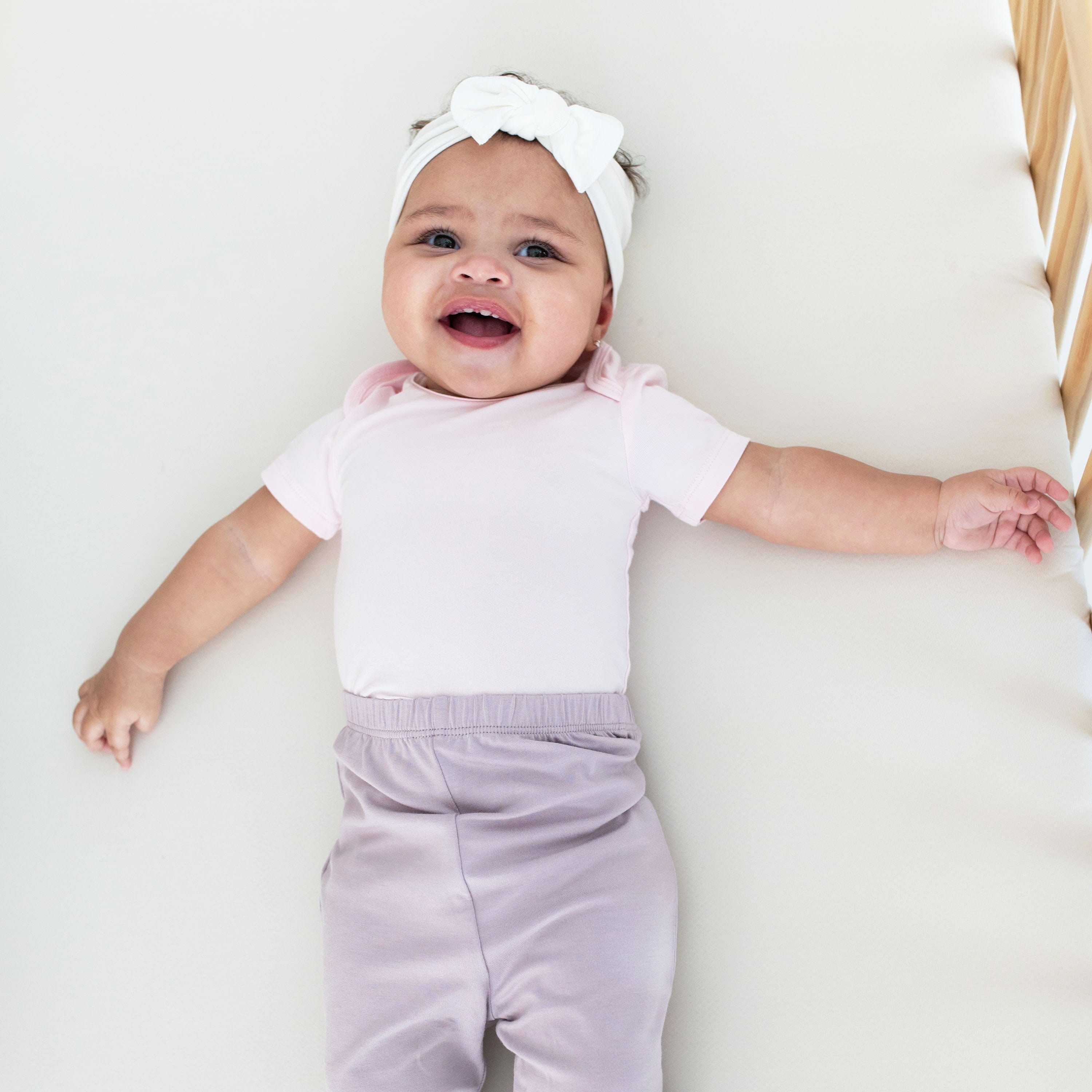 Infant wearing short sleeve Kyte Baby Bodysuit onesie in Sakura