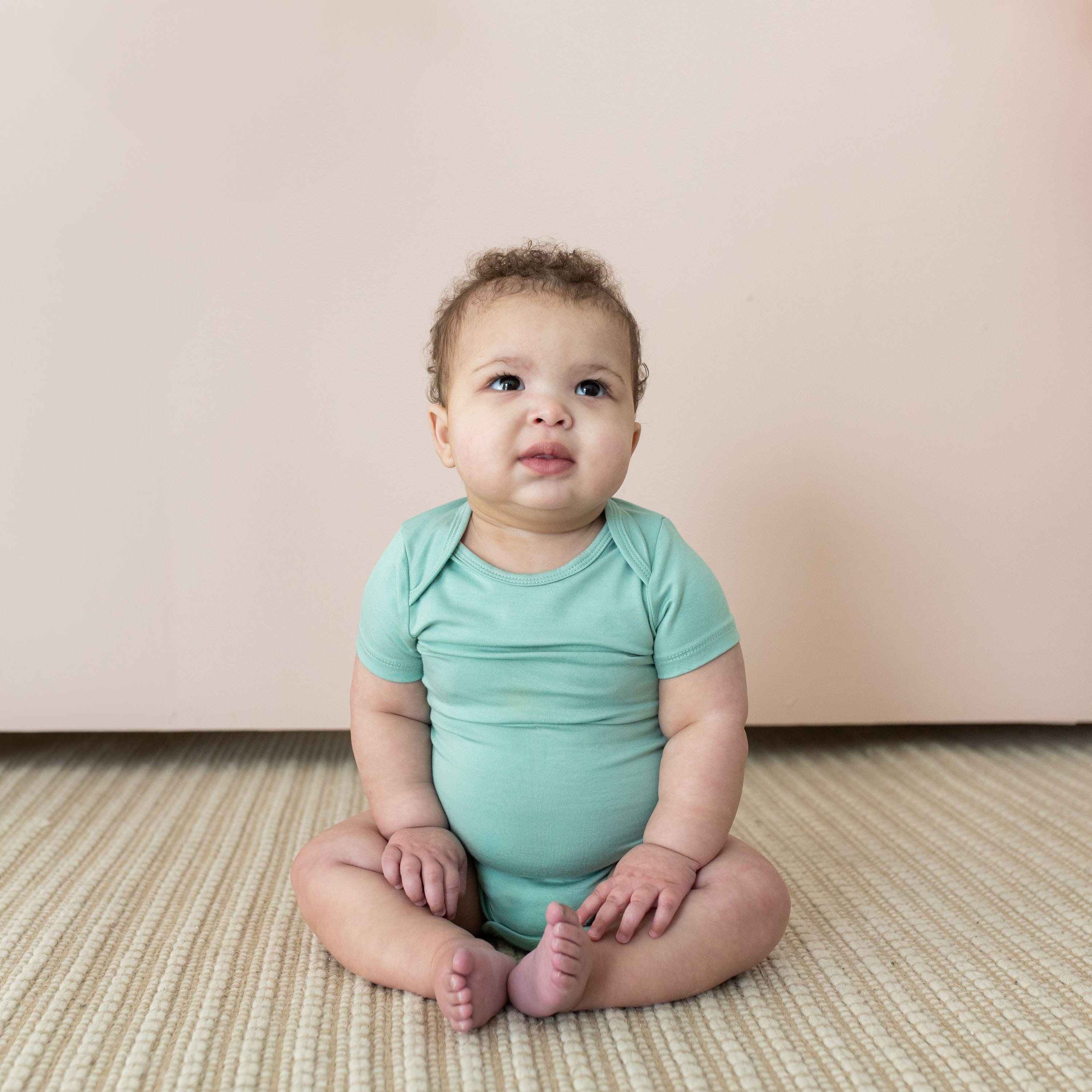 Infant wearing Kyte Baby short Bodysuit in Wasabi