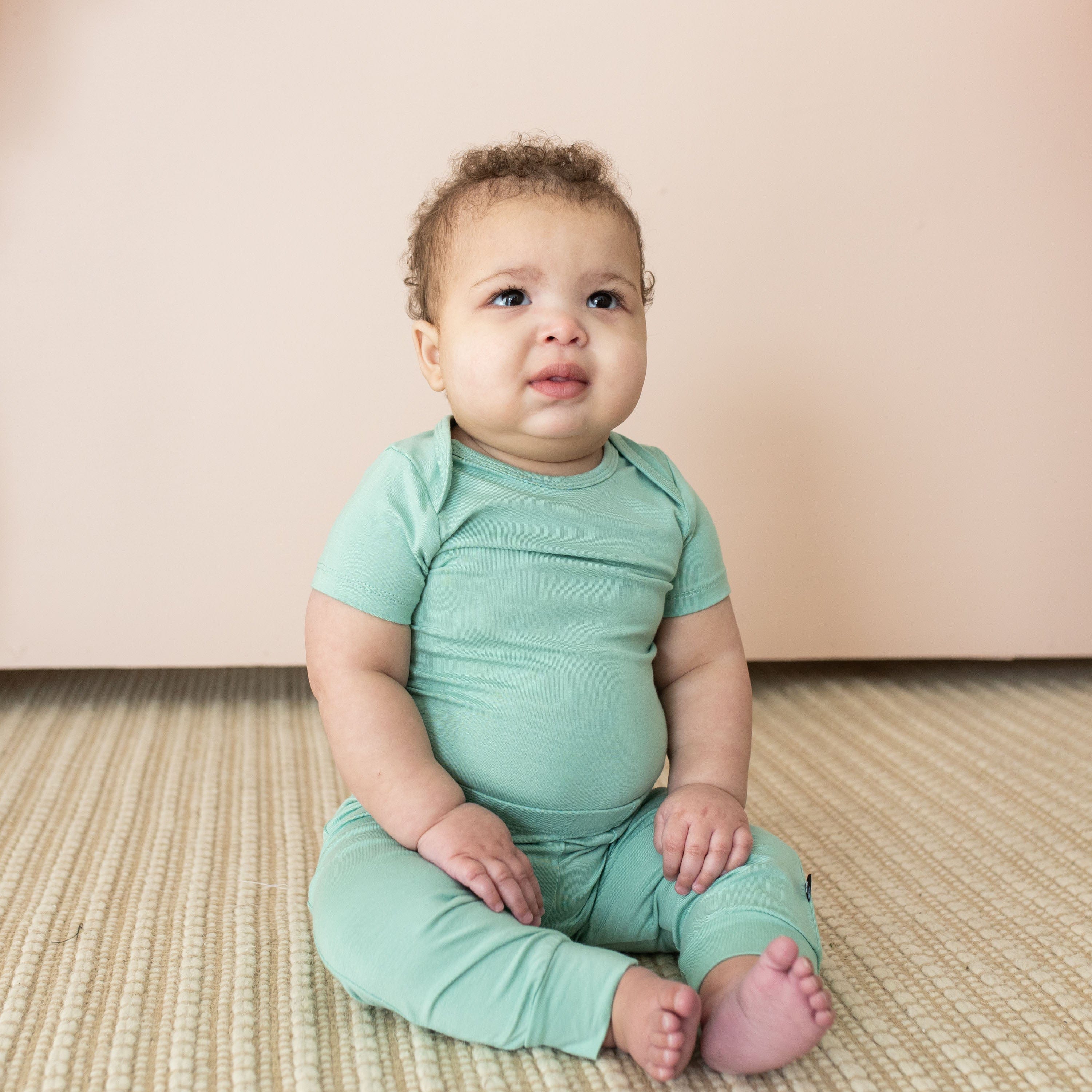 Infant wearing short sleeve Kyte Baby Bodysuit in Wasabi green