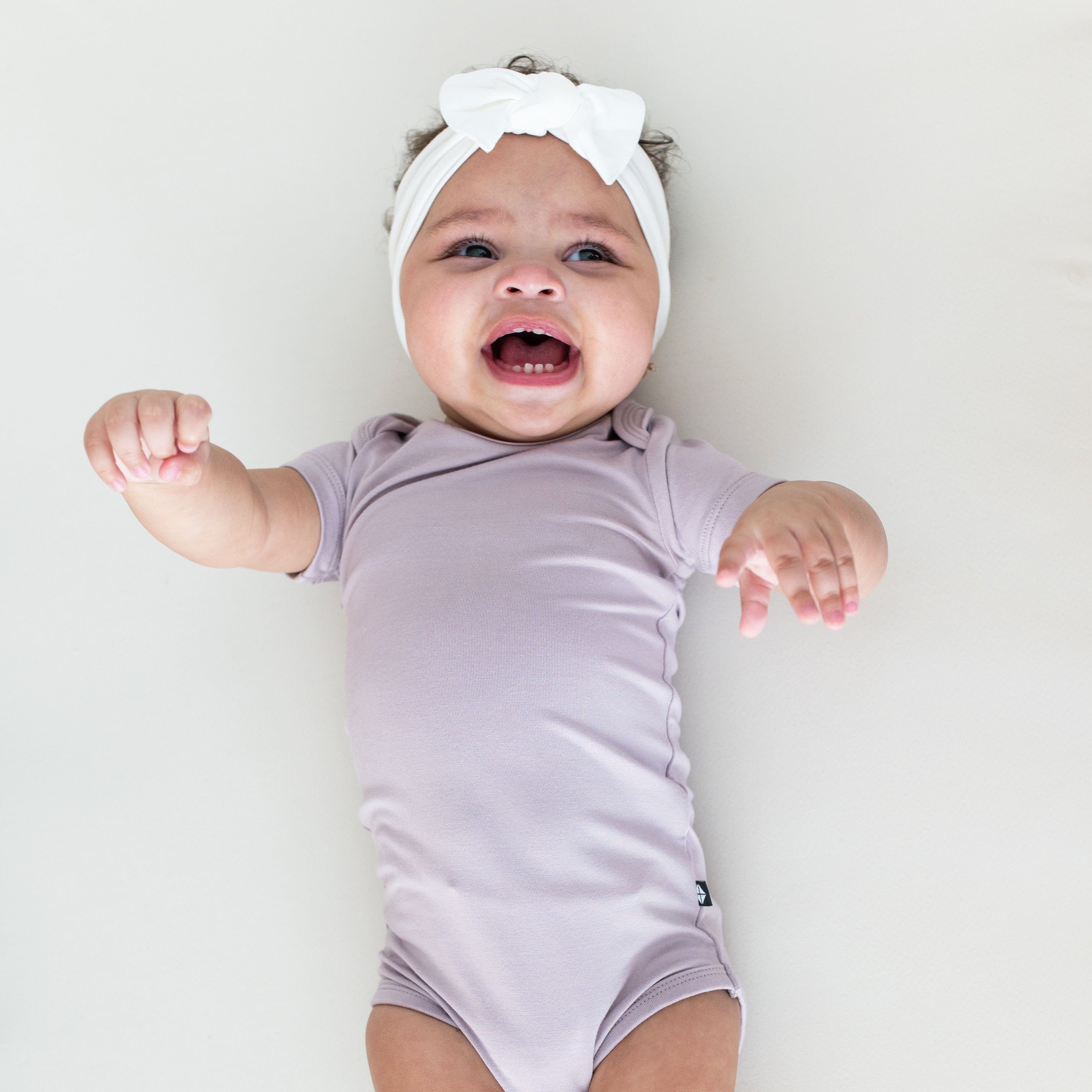 Infant wearing Kyte Baby short Bodysuit in Wisteria