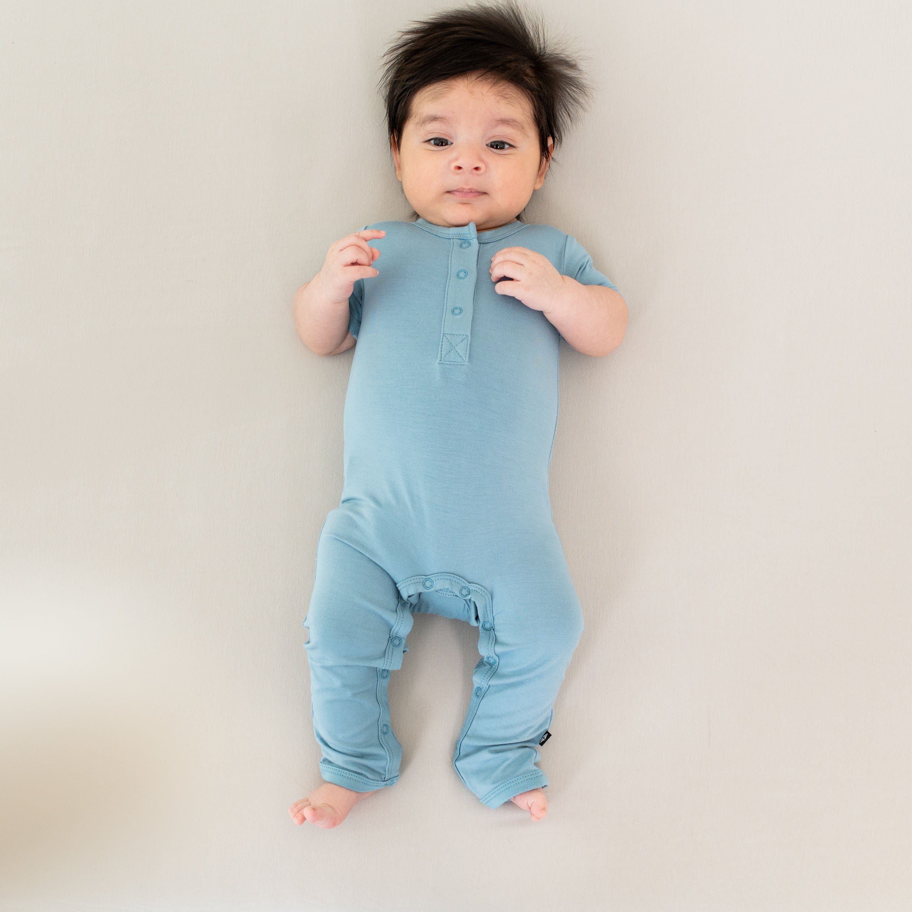 Baby wearing Kyte Baby bamboo Short Sleeve Snap Romper in Dusty Blue