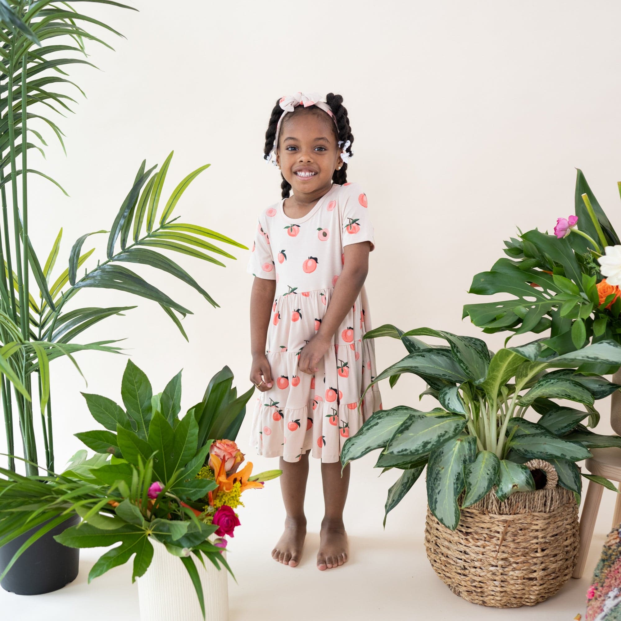 Girl wearing Kyte Baby Short Sleeve Tiered Dress in Peach
