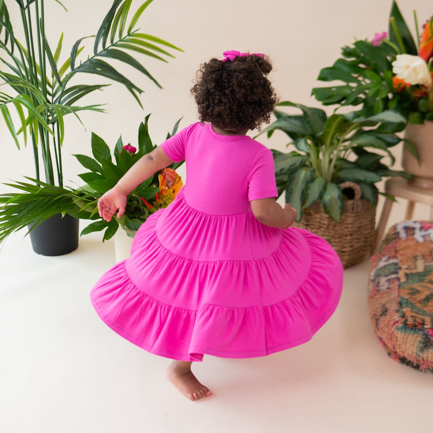 Girl wearing Kyte Baby Short Sleeve Tiered Dress in Raspberry pink