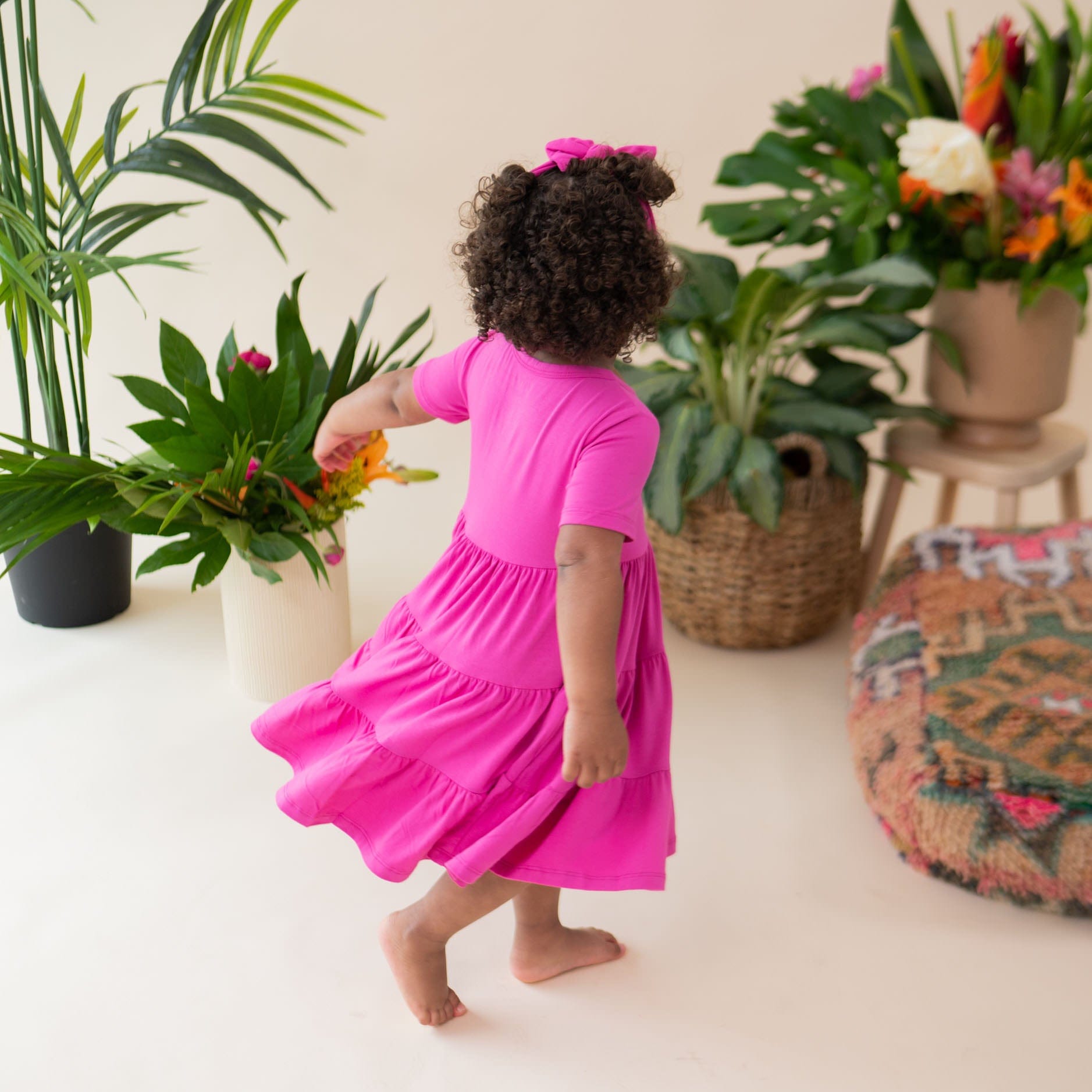 Toddler twirling in Kyte Baby Short Sleeve Tiered Dress in Raspberry