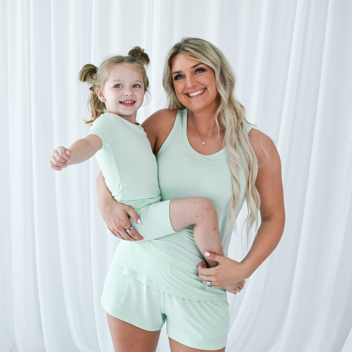 Mom and child wearing Kyte Baby coordinating pajama sets in Mint