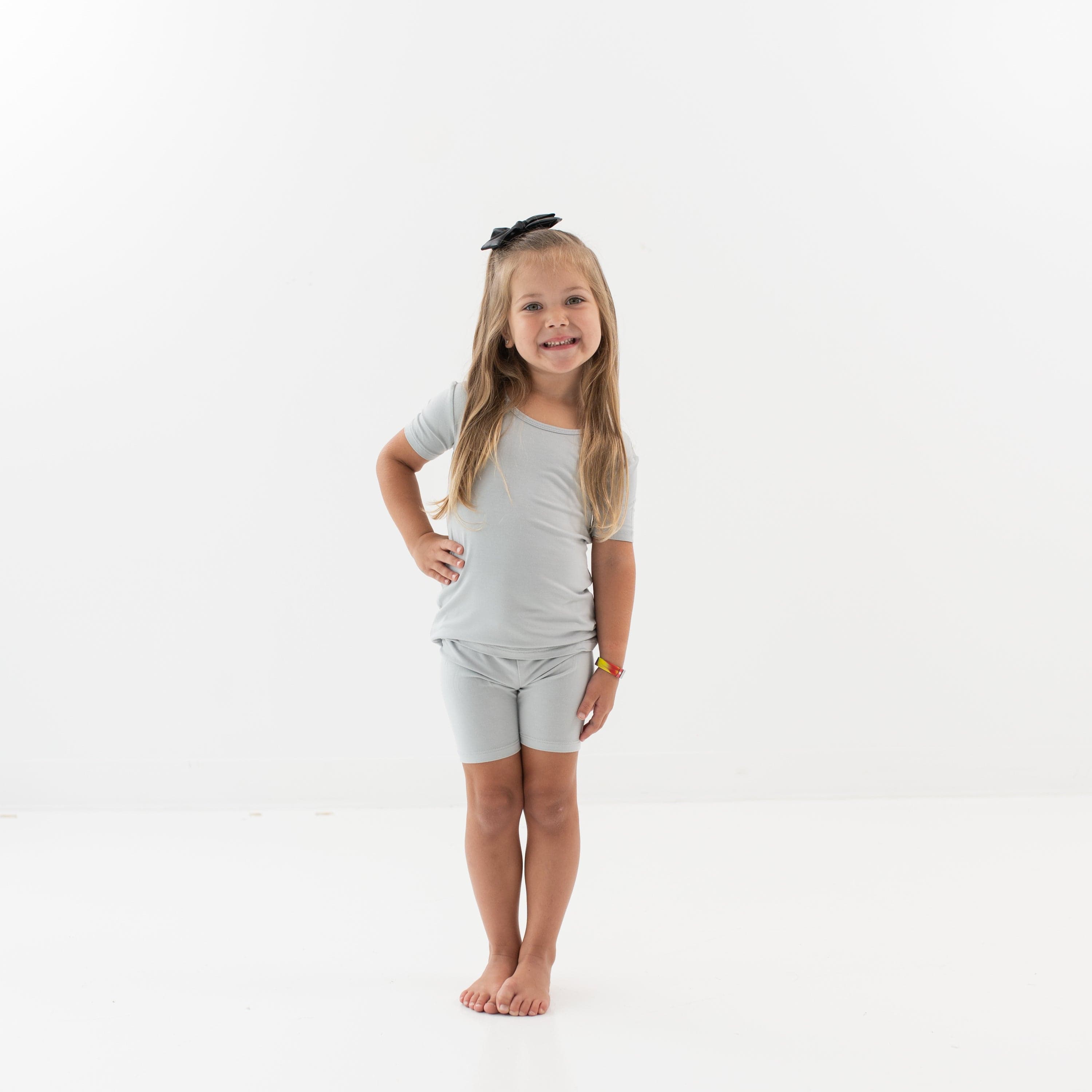 Smiling toddler wearing two piece Short Sleeve Pajamas in Storm and a Bow in Midnight