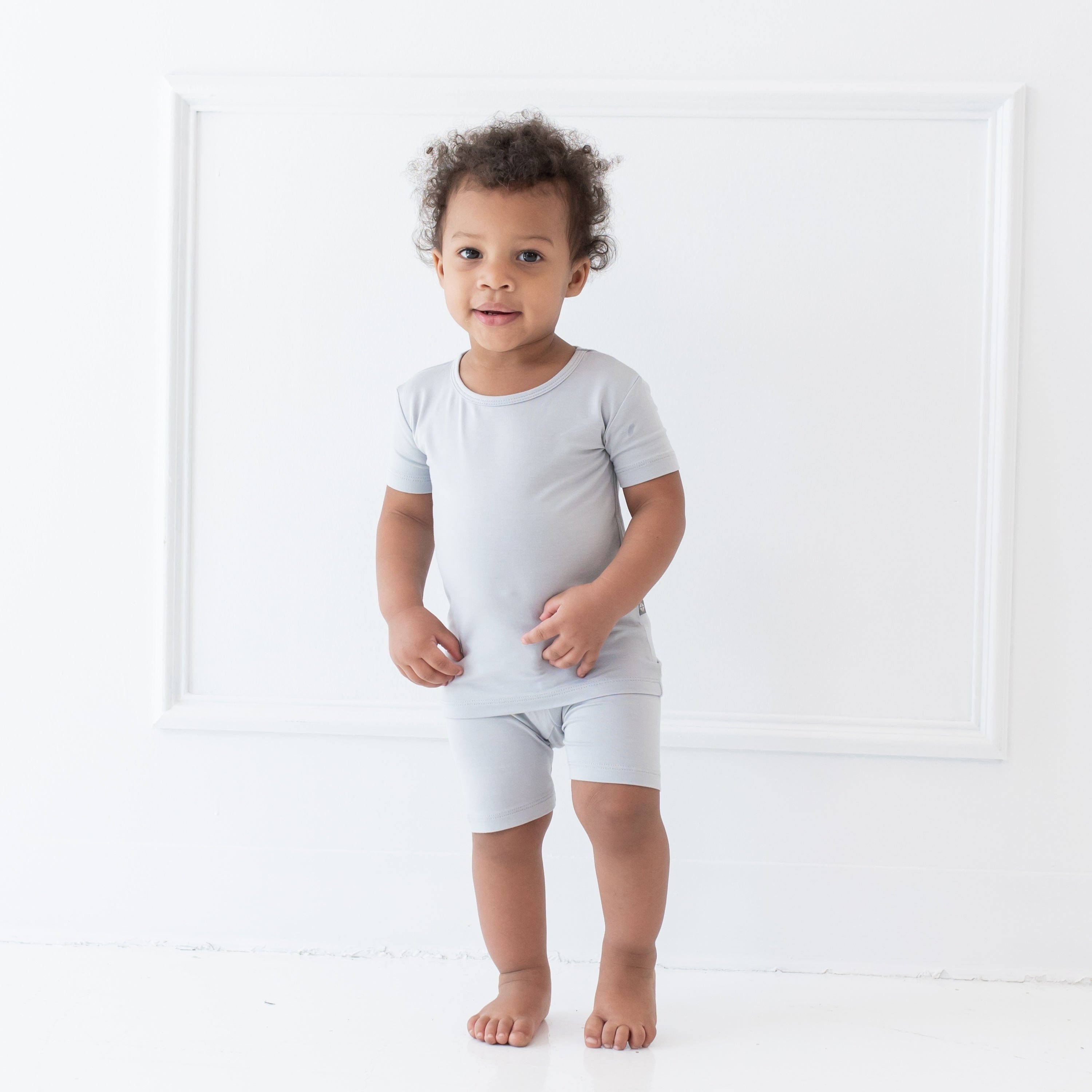 Standing toddler in front of a white wall wearing Short Sleeve Pajama Set in Storm