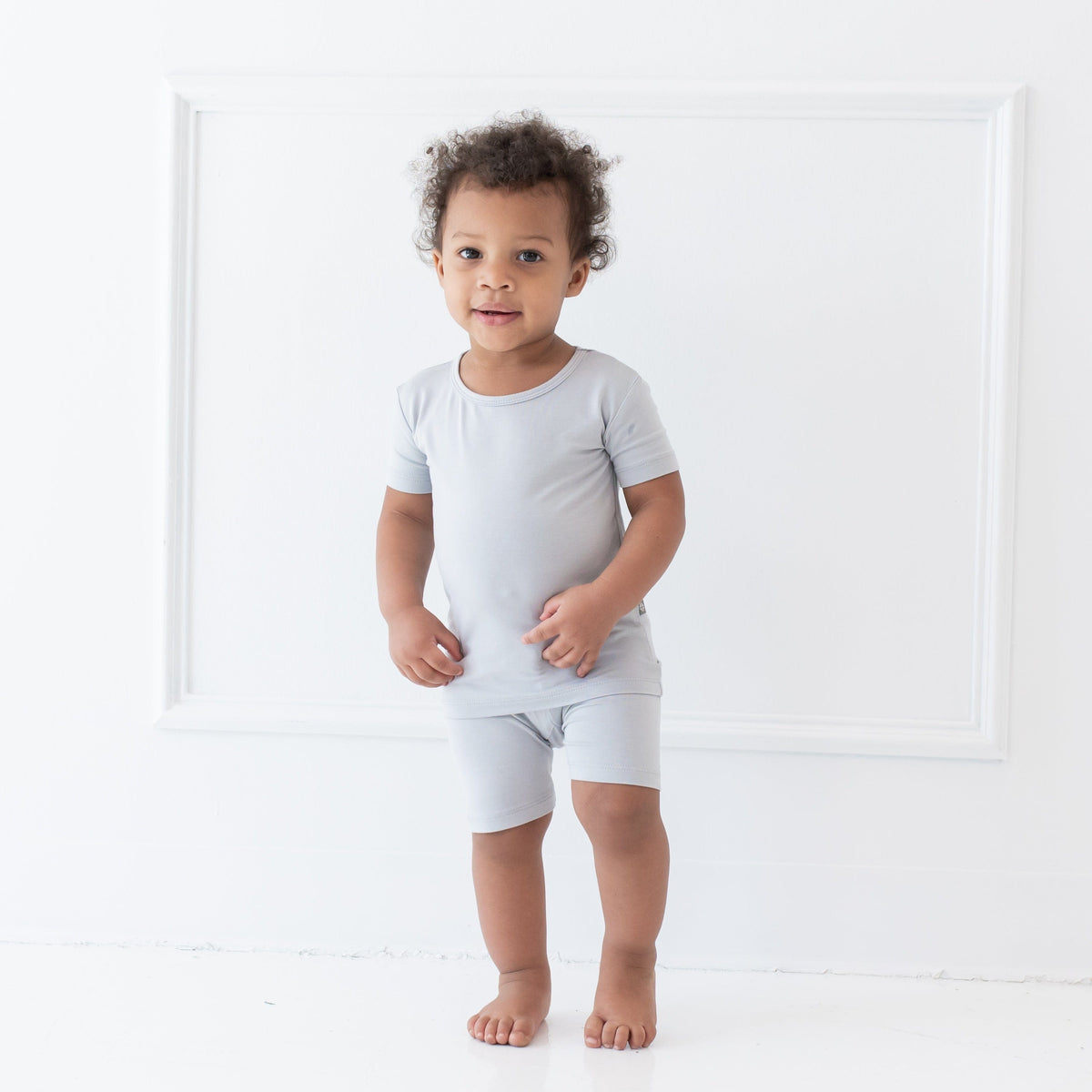 Standing toddler in front of a white wall wearing Short Sleeve Pajama Set in Storm