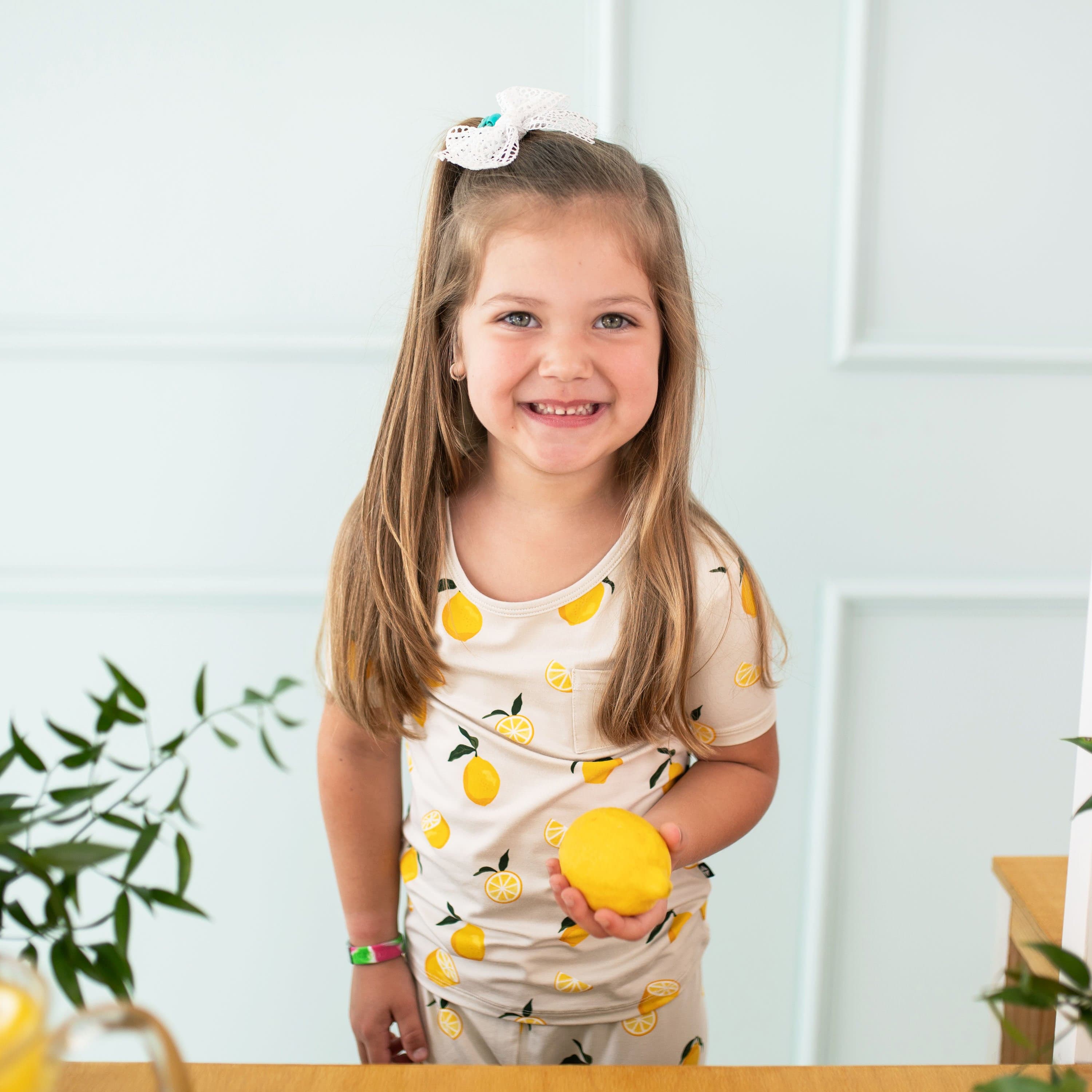 Girl wearing Kyte Baby Short Sleeve Pajamas in Lemon pattern