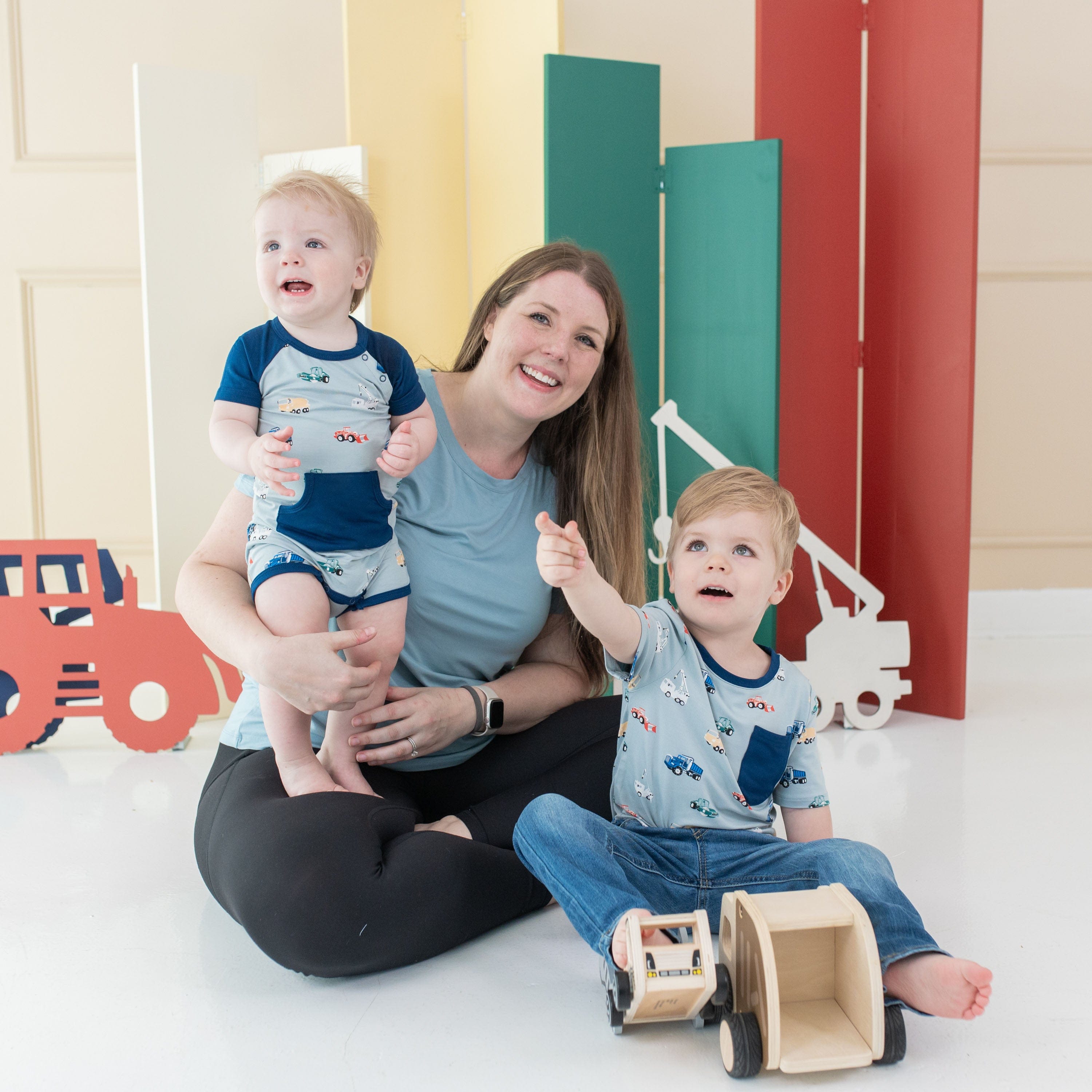 Mom with sons wearing Kyte Baby matching family outfits in Construction pattern
