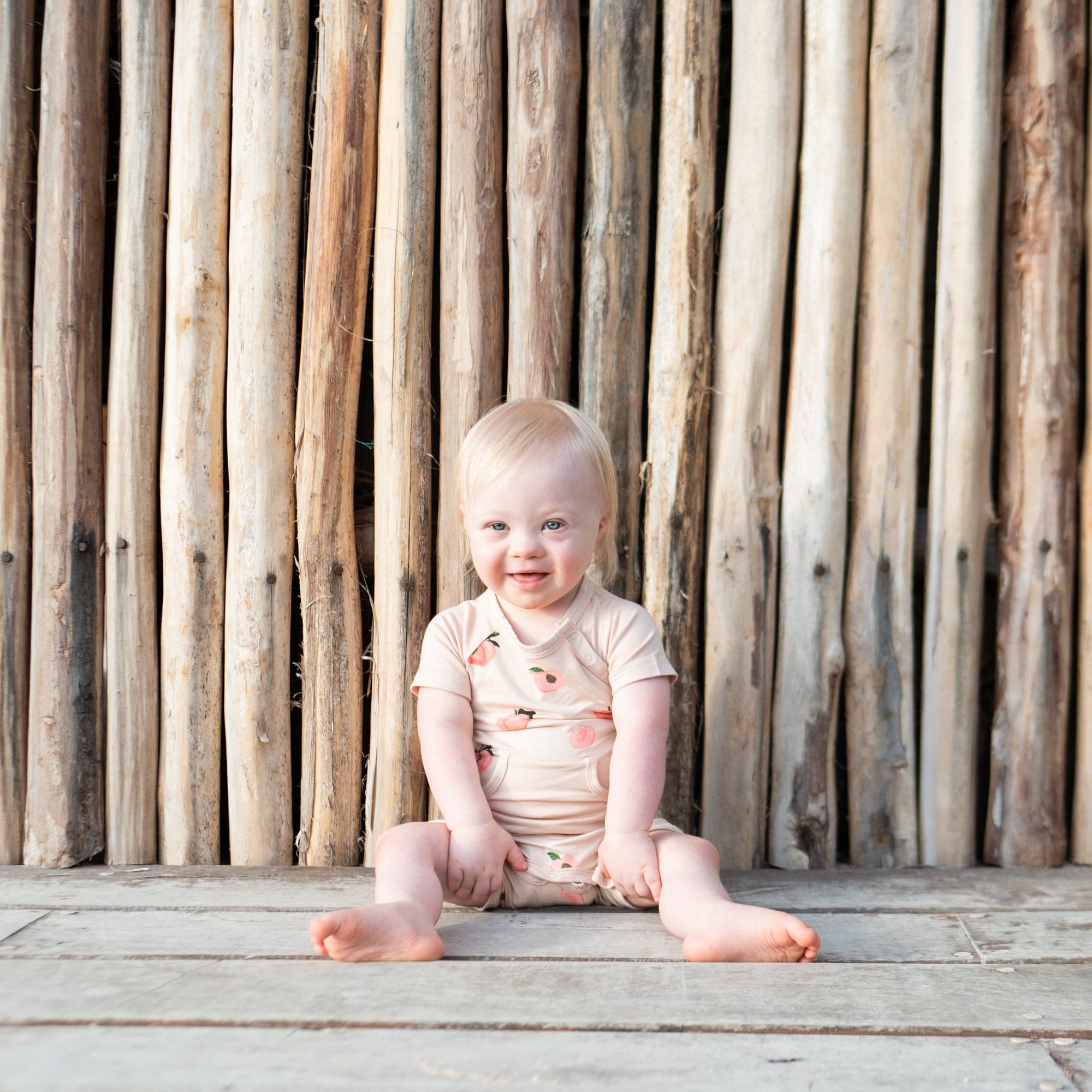 Infant wearing Kyte Baby Shortall in Peach